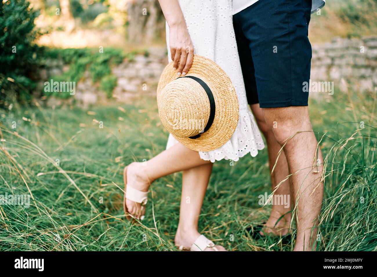 Chapeau de paille dans la main de la femme debout à côté de l'homme dans le jardin. Rogné. Sans visage Banque D'Images