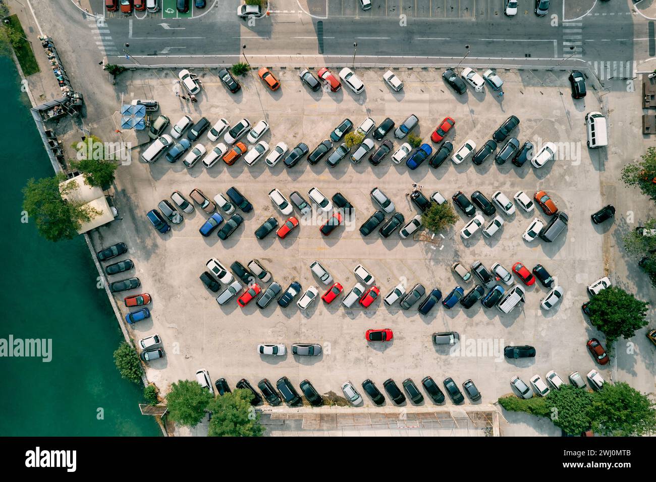 Grand parking avec des voitures colorées debout dans les rangées sur le bord de la mer. Drone Banque D'Images