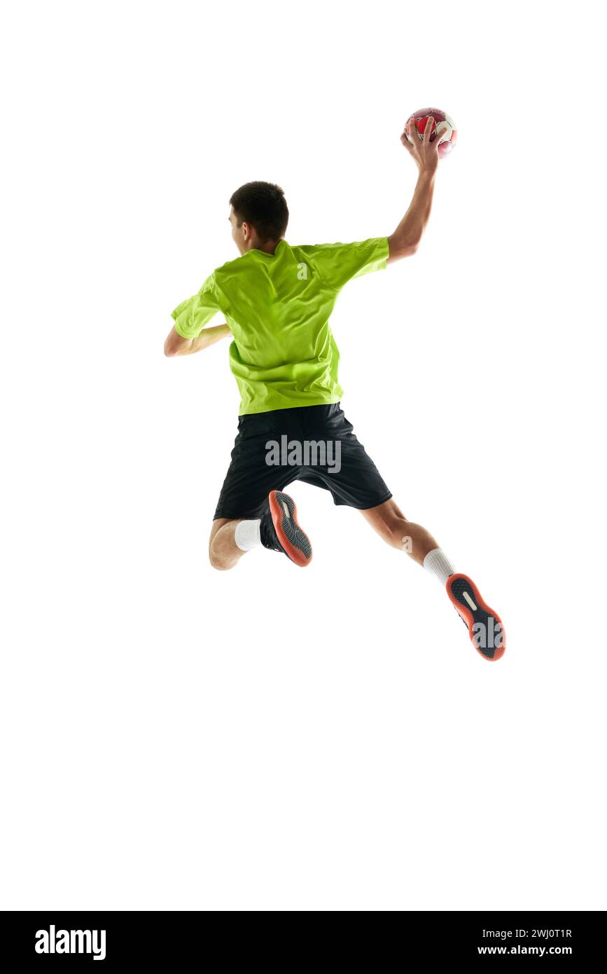 Image pleine longueur d'un jeune athlète de handball en mouvement pendant le match, jetant la balle sur fond blanc de studio. Motivation pour gagner Banque D'Images