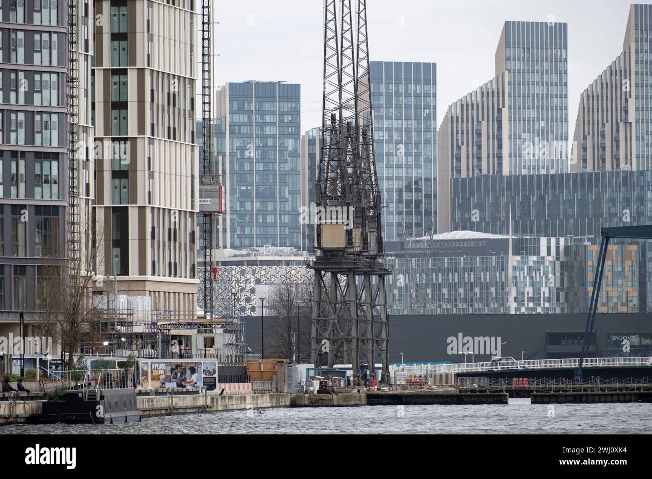 Nouveaux immeubles de grande hauteur à North Greenwich vus du cœur du quartier financier de Canary Wharf à travers South Dock le 6 février 2024 à Londres, Royaume-Uni. Les anciennes grues Stothert & Pitt se trouvent toujours là où elles faisaient partie des quais de travail dans les Docklands. Banque D'Images