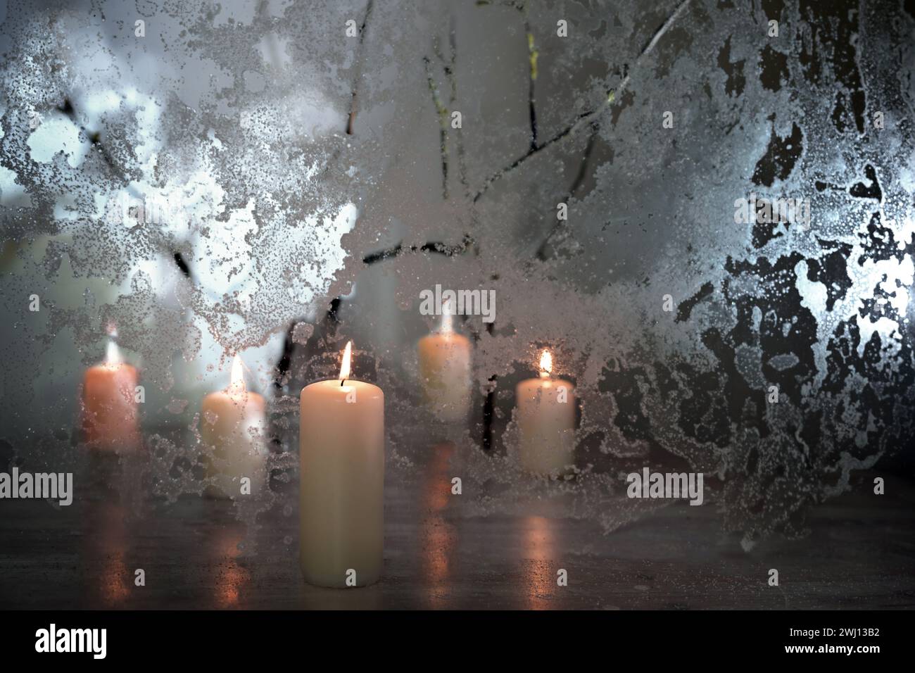 Cinq bougies avec une lumière chaude et du verre gelé avec un éclairage dramatique comme décoration d'hiver pour les vacances d'hiver à Noël Banque D'Images