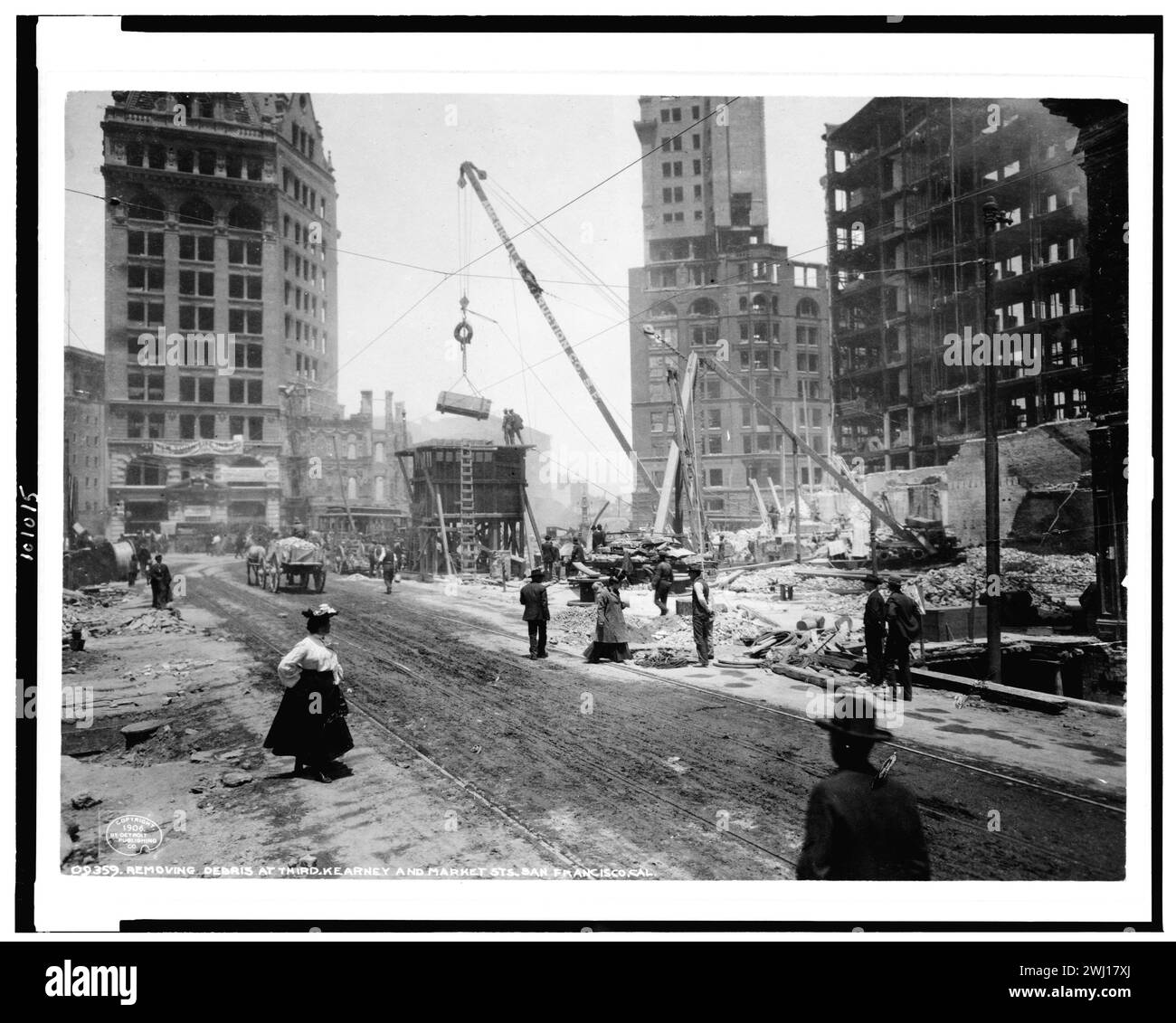 Tremblement de terre de 1906 à San Francisco. Vue après un tremblement de terre et un incendie, montrant des gravats en mouvement de grue, comme plusieurs hommes et une femme passent. Banque D'Images