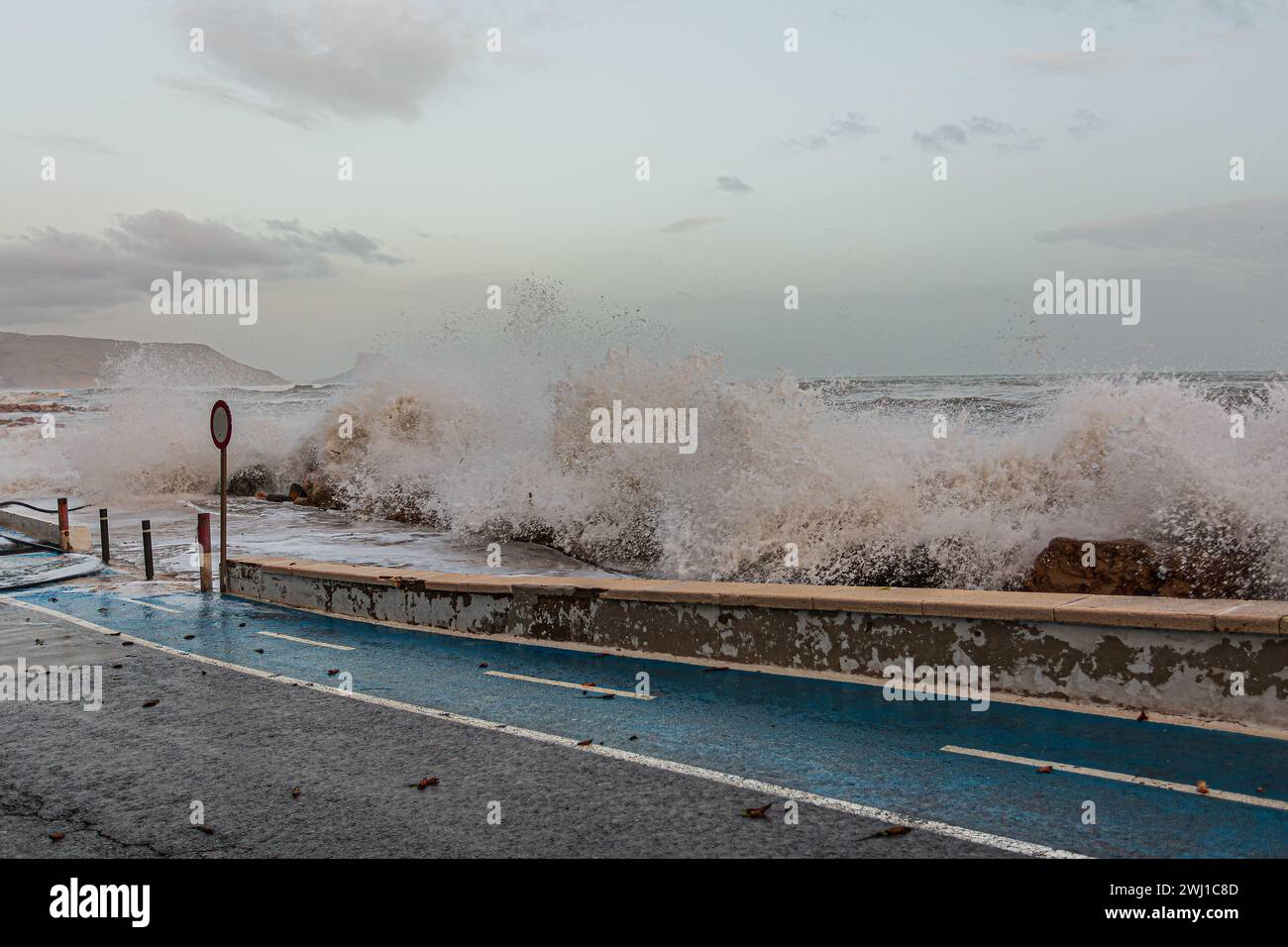 Une vague océanique éclaboussant sur la route avec un parcmètre. Banque D'Images