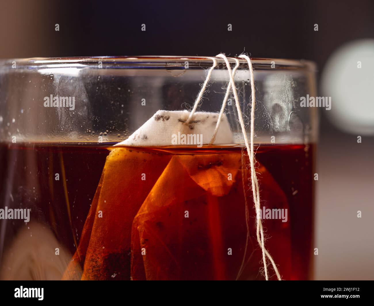 Un sachet de thé suspendu dans un verre de thé placé sur une table Banque D'Images
