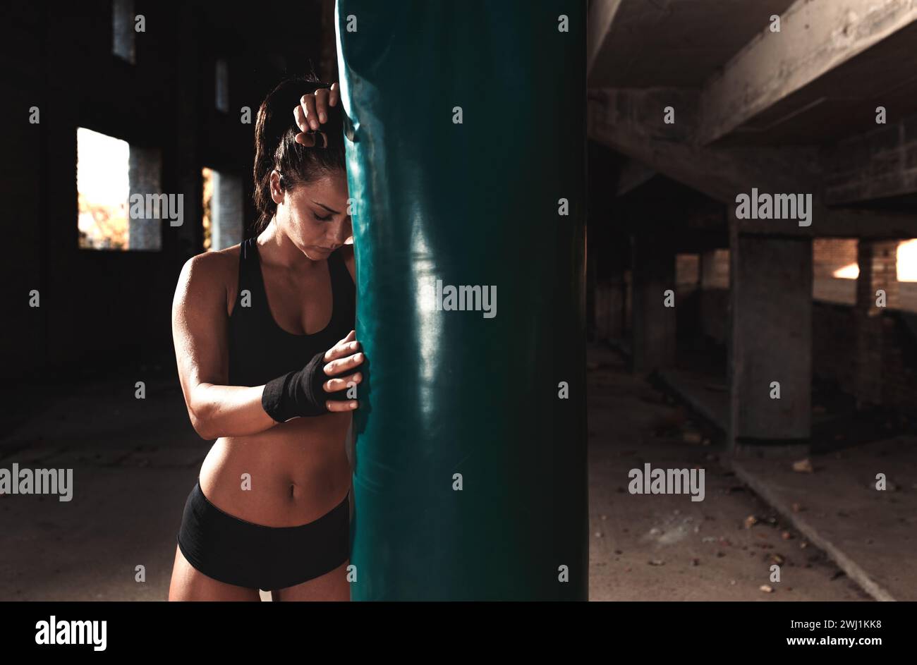 Boxeur féminin poinçonnant un sac de boxe dans l'entrepôt. Banque D'Images