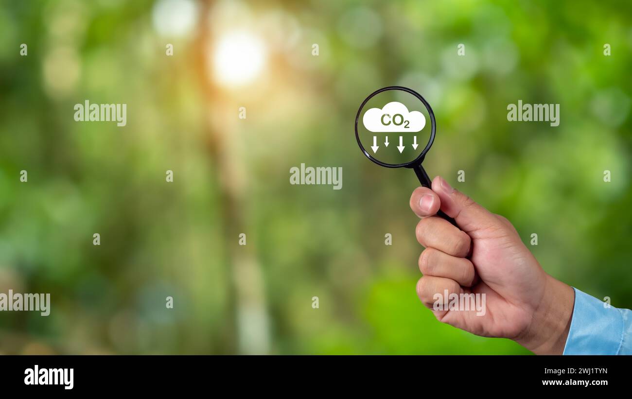 Un environnement propre et convivial sans émissions de dioxyde de carbone, main tenant une loupe avec icône de réduction de CO2 à l'intérieur, crédit carbone à limi Banque D'Images