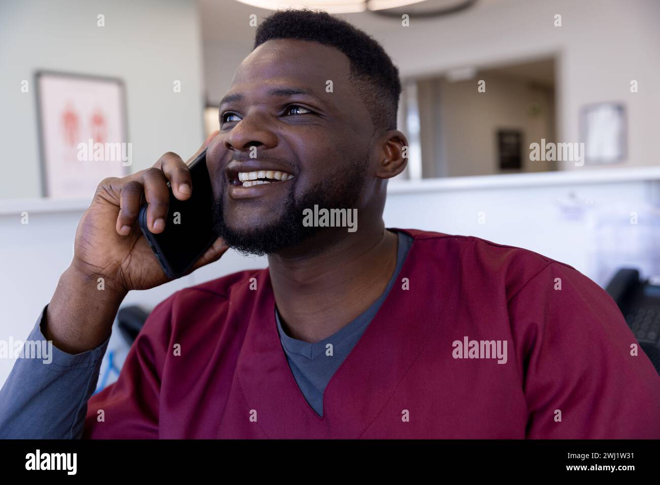 Heureux médecin afro-américain parlant sur smartphone à la réception de l'hôpital Banque D'Images