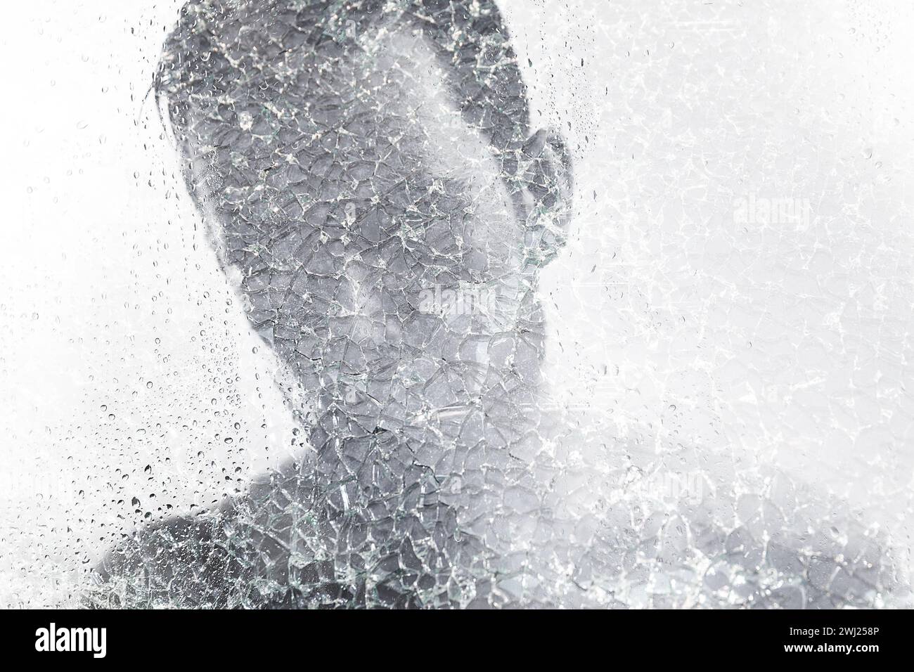 Homme derrière du verre mouillé et fissuré. Concepts de troubles mentaux ou autres problèmes sociaux affectant la personnalité humaine Banque D'Images
