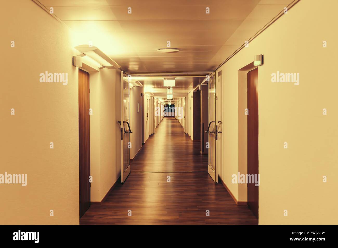 Long couloir éclairé, couloir, dans le bâtiment résidentiel, clinique, maison de retraite, Banque D'Images