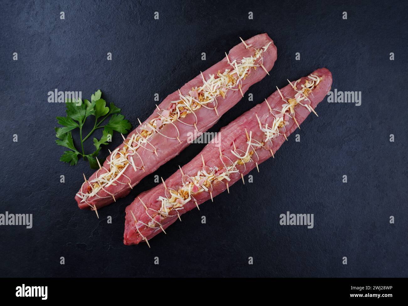 Filet de porc cru Mangalica farci de noix hachées et de citrouille offert comme vue de dessus sur un tableau noir design avec copie spa Banque D'Images