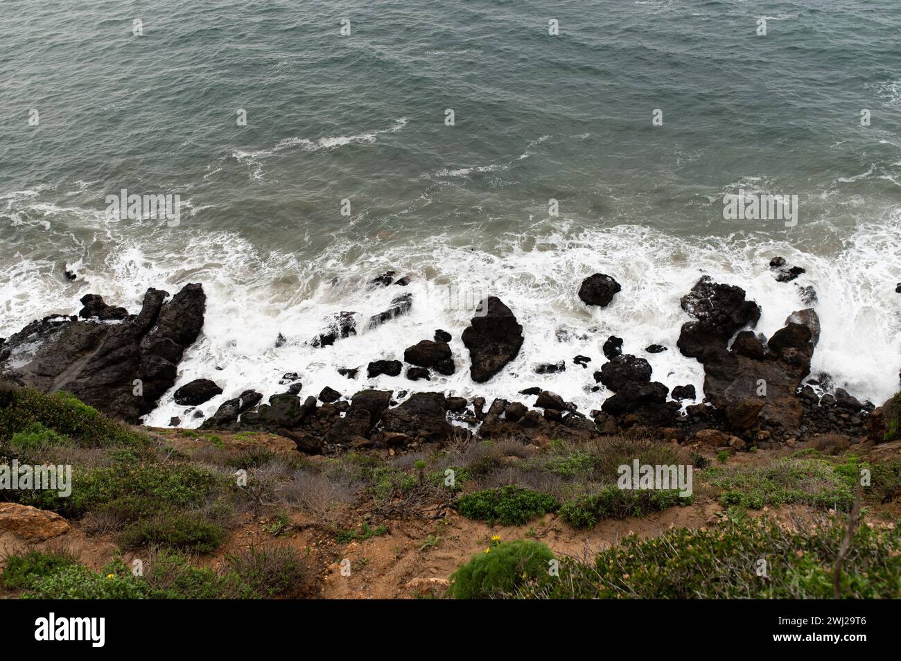 Côte rocheuse avec des vagues mousseuses Banque D'Images