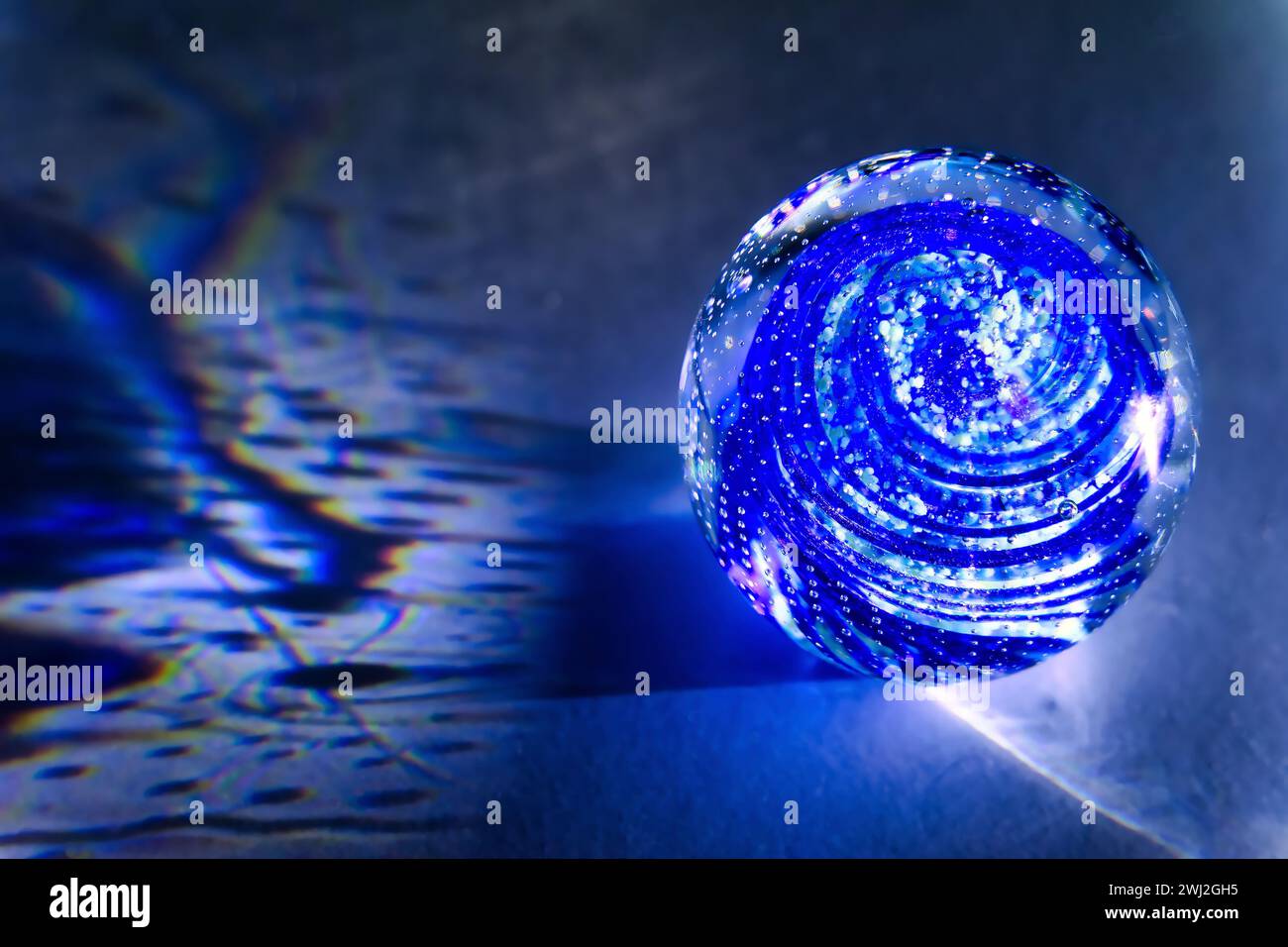 Une boule de verre transparente avec inclusions projette de vraies ombres sur un fond blanc Banque D'Images