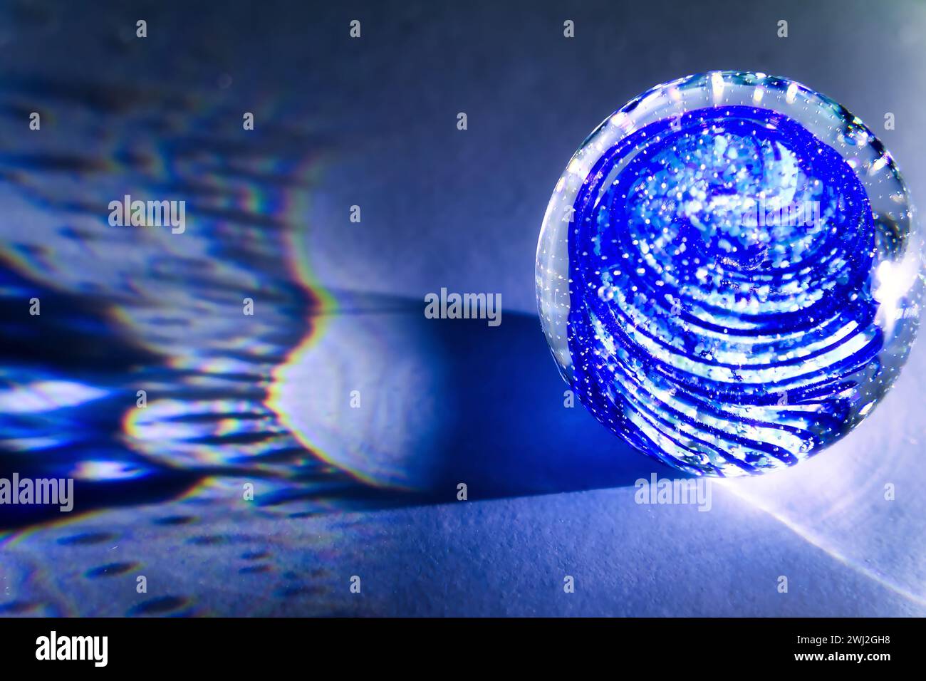 Une boule de verre transparente avec inclusions projette de vraies ombres sur un fond blanc Banque D'Images