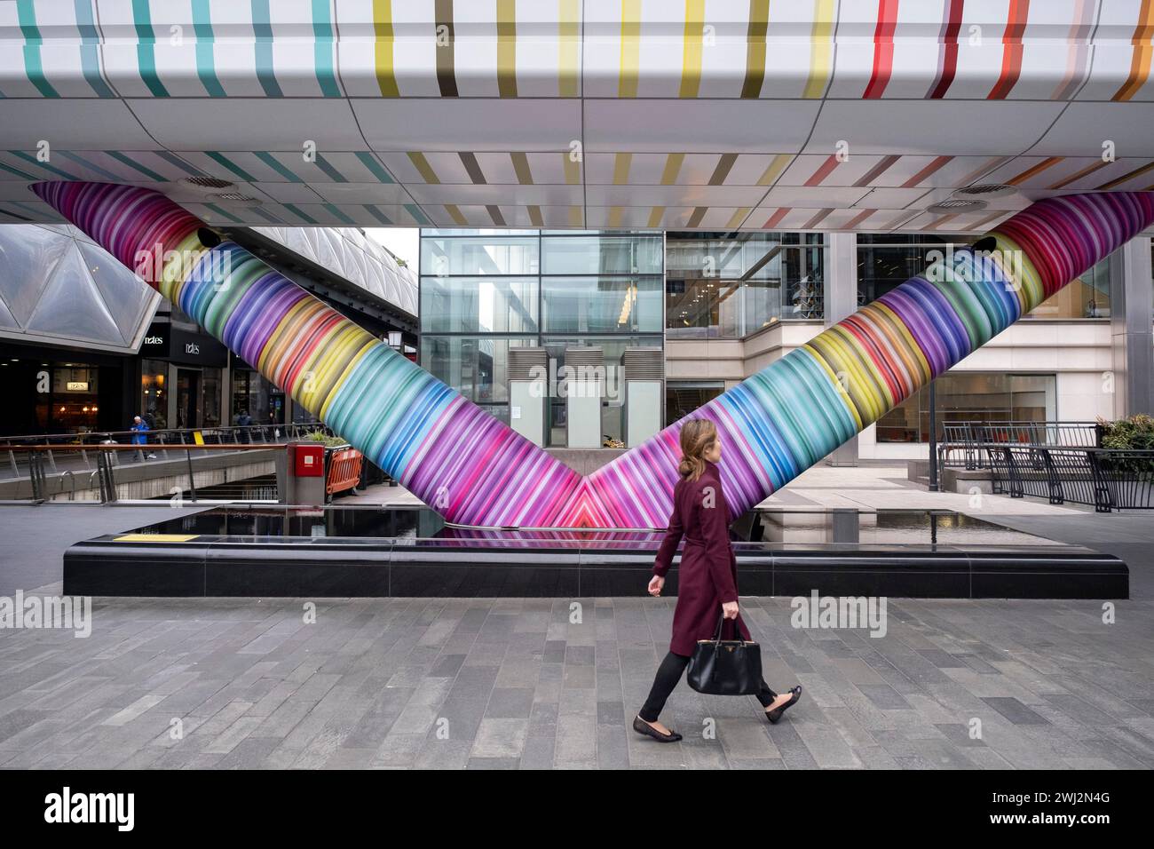 Les personnes interagissant avec l’œuvre d’art public géométrique « Click Your Heels Together Three Times » de l’artiste Adam Nathaniel Furman à l’extérieur de la passerelle du tunnel à Adams Plaza Bridge reliant North Collonade à Crossrail place au cœur du quartier financier de Canary Wharf le 6 février 2024 à Londres, Royaume-Uni. Canary Wharf est une zone située près de l'île des chiens dans le quartier londonien de Tower Hamlets et est définie par la Greater London Authority comme faisant partie du quartier central des affaires de Londres. Banque D'Images