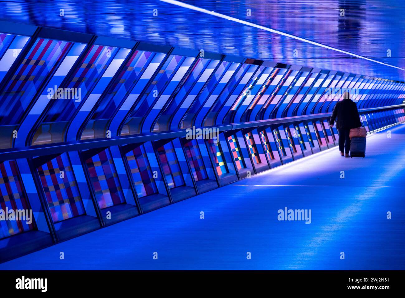 Des personnes interagissant avec l’œuvre d’art contemporain publique géométrique captivée par Colour par l’artiste Camille Walala dans la passerelle du tunnel à Adams Plaza Bridge reliant North Collonade à Crossrail place au cœur du quartier financier de Canary Wharf le 6 février 2024 à Londres, Royaume-Uni. Canary Wharf est une zone située près de l'île des chiens dans le quartier londonien de Tower Hamlets et est définie par la Greater London Authority comme faisant partie du quartier central des affaires de Londres. Banque D'Images