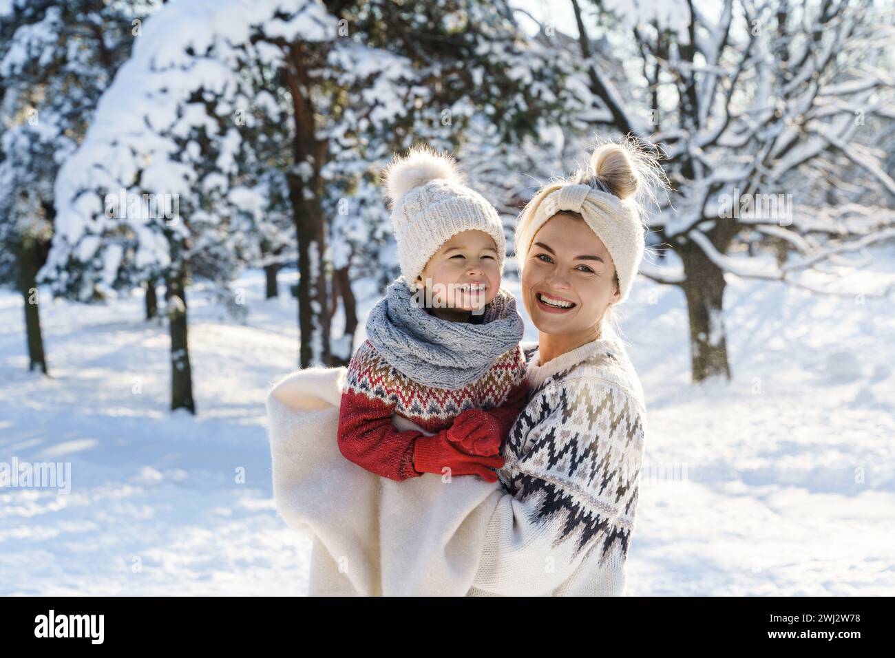 Heureuse mère et son petit fils mignon portant des pulls chauds pendant la journée ensoleillée d'hiver Banque D'Images