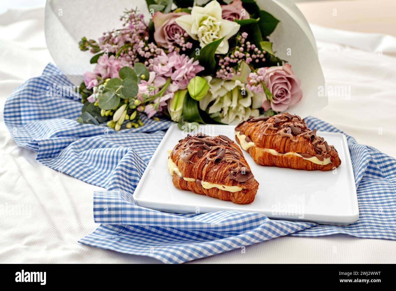 Cadre romantique avec croissants au chocolat et bouquet de fleurs Banque D'Images