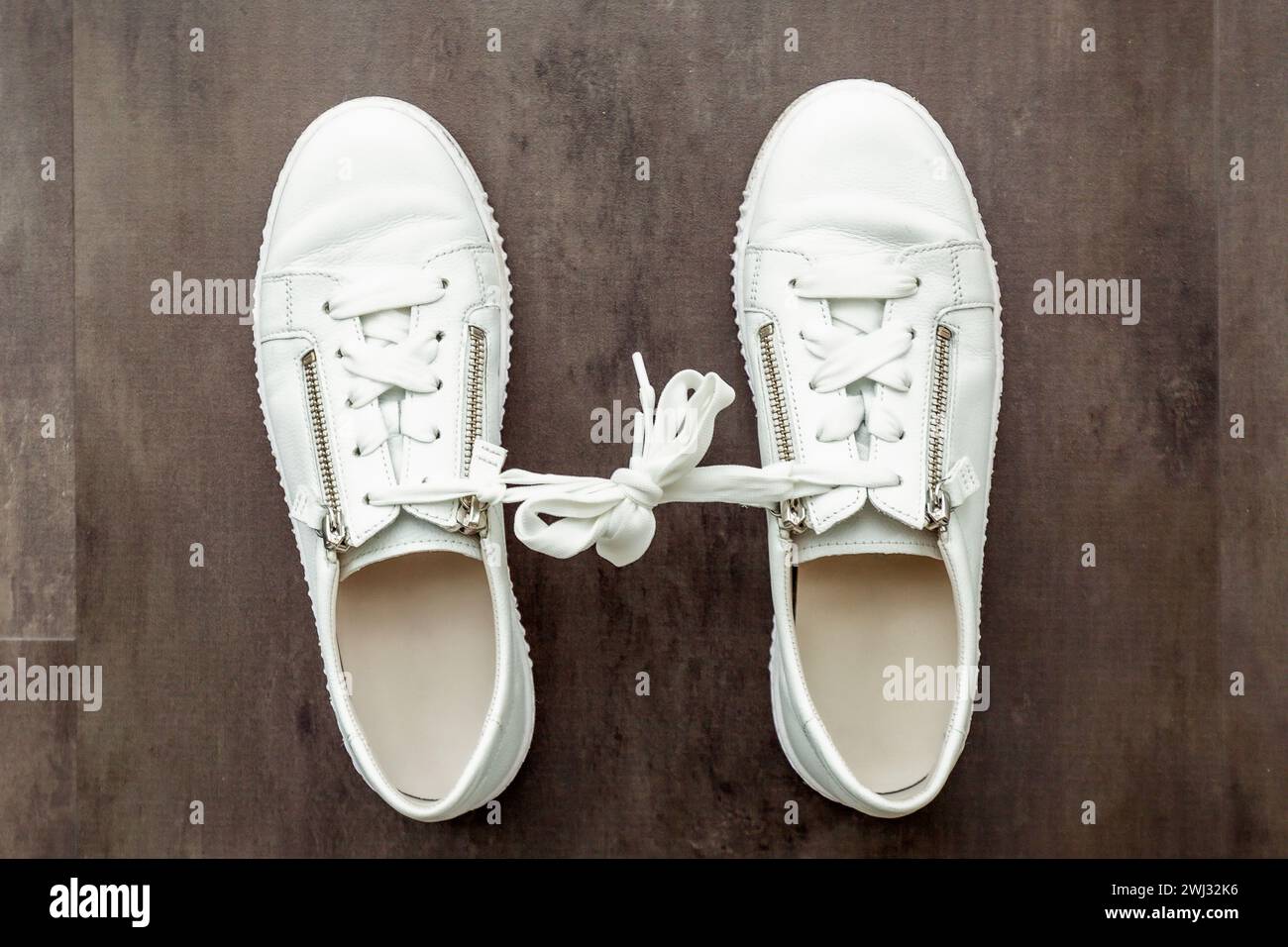 Gamophobie. peur du concept d'engagement. Une paire de chaussures blanches, sneaker sur fond de bois. Lié Banque D'Images