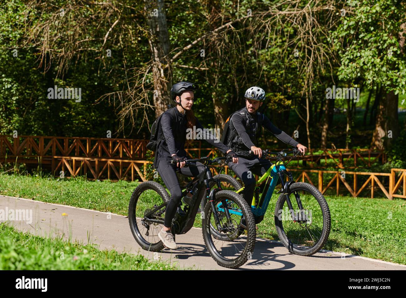 Un couple heureux, orné de matériel cycliste professionnel, profite d'une balade romantique à vélo à travers un parc, entouré de nat moderne Banque D'Images