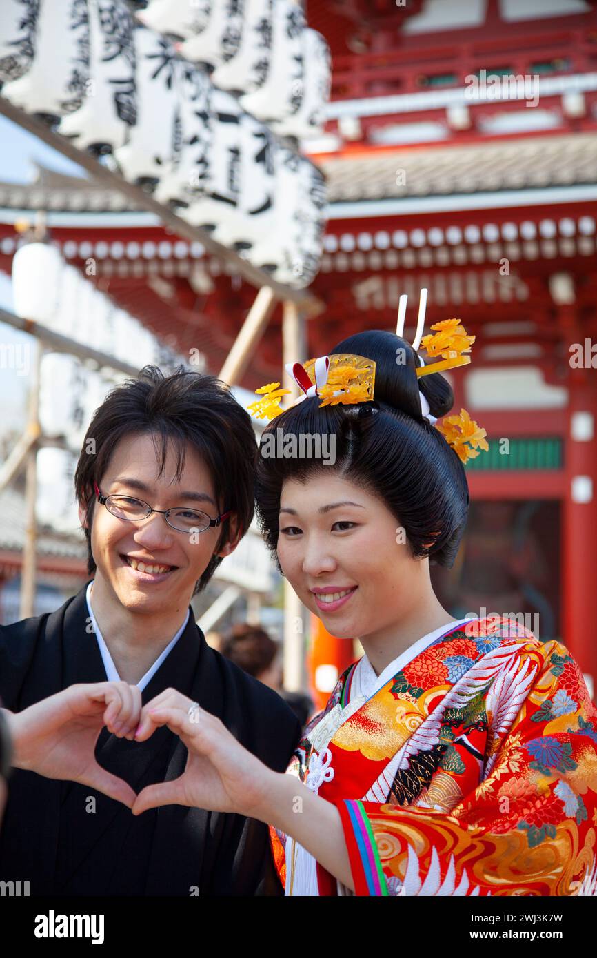 Un couple asiatique pose pour des photographies au temple Sensoji à Asakusa, Tokyo, Japon. Les deux sont habillés en costume traditionnel japonais. Banque D'Images