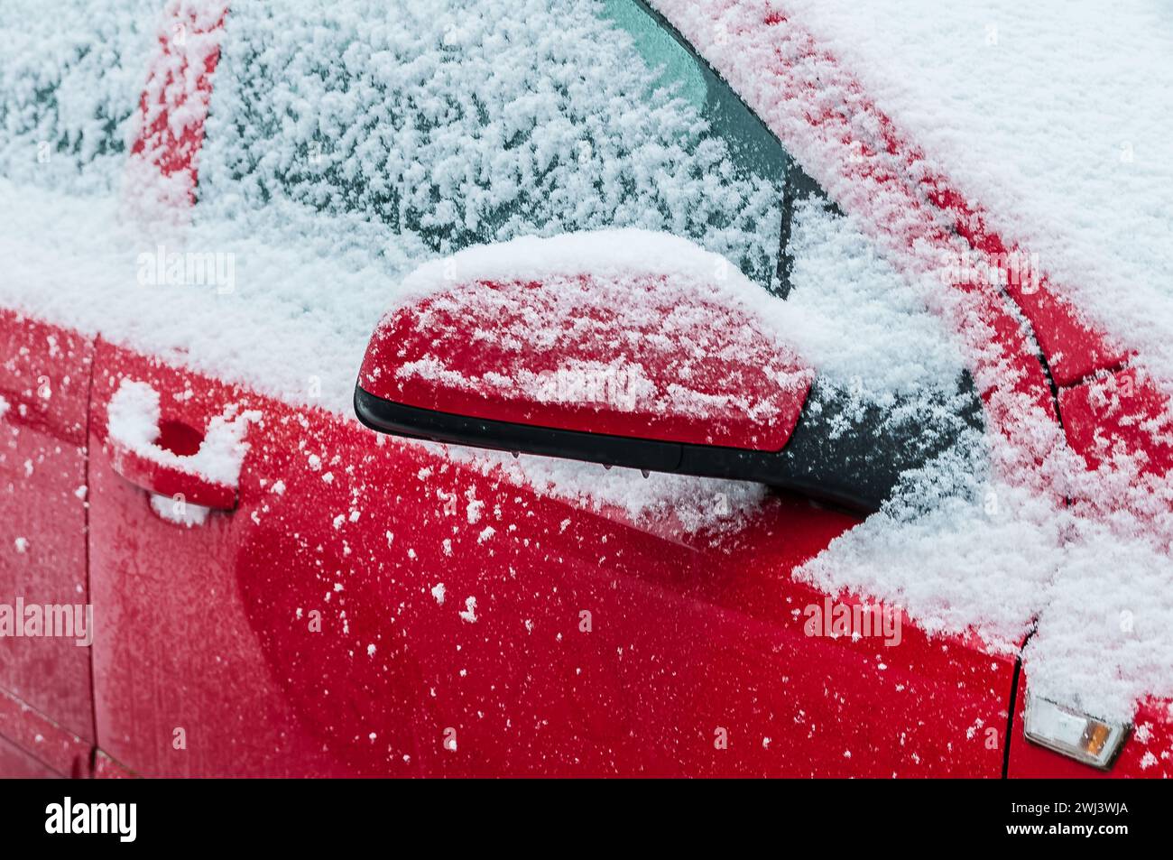 Une voiture rouge en hiver avec de la neige et de la glace Banque D'Images