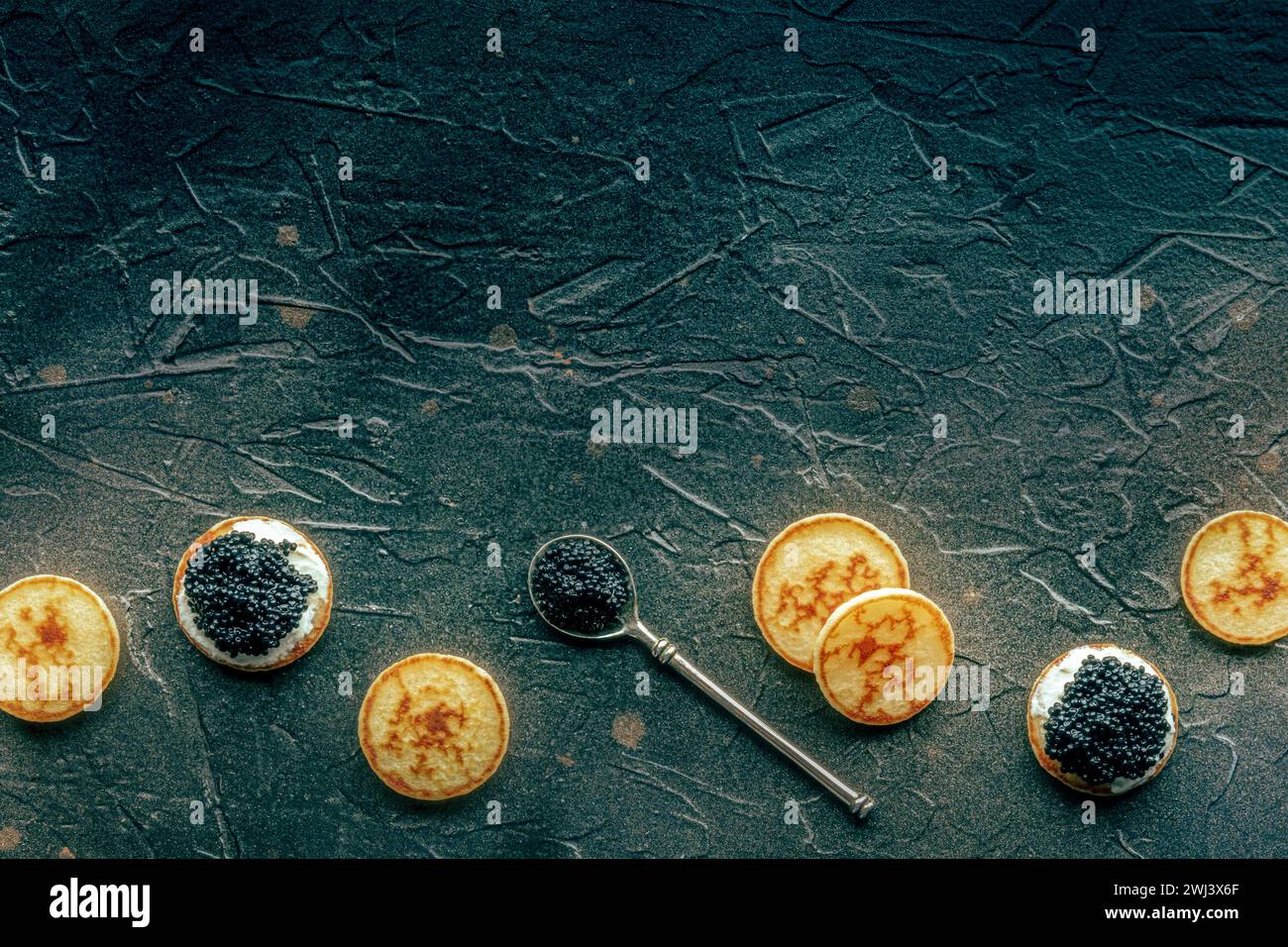 Blinis au caviar noir et fromage à la crème, top shot sur noir Banque D'Images