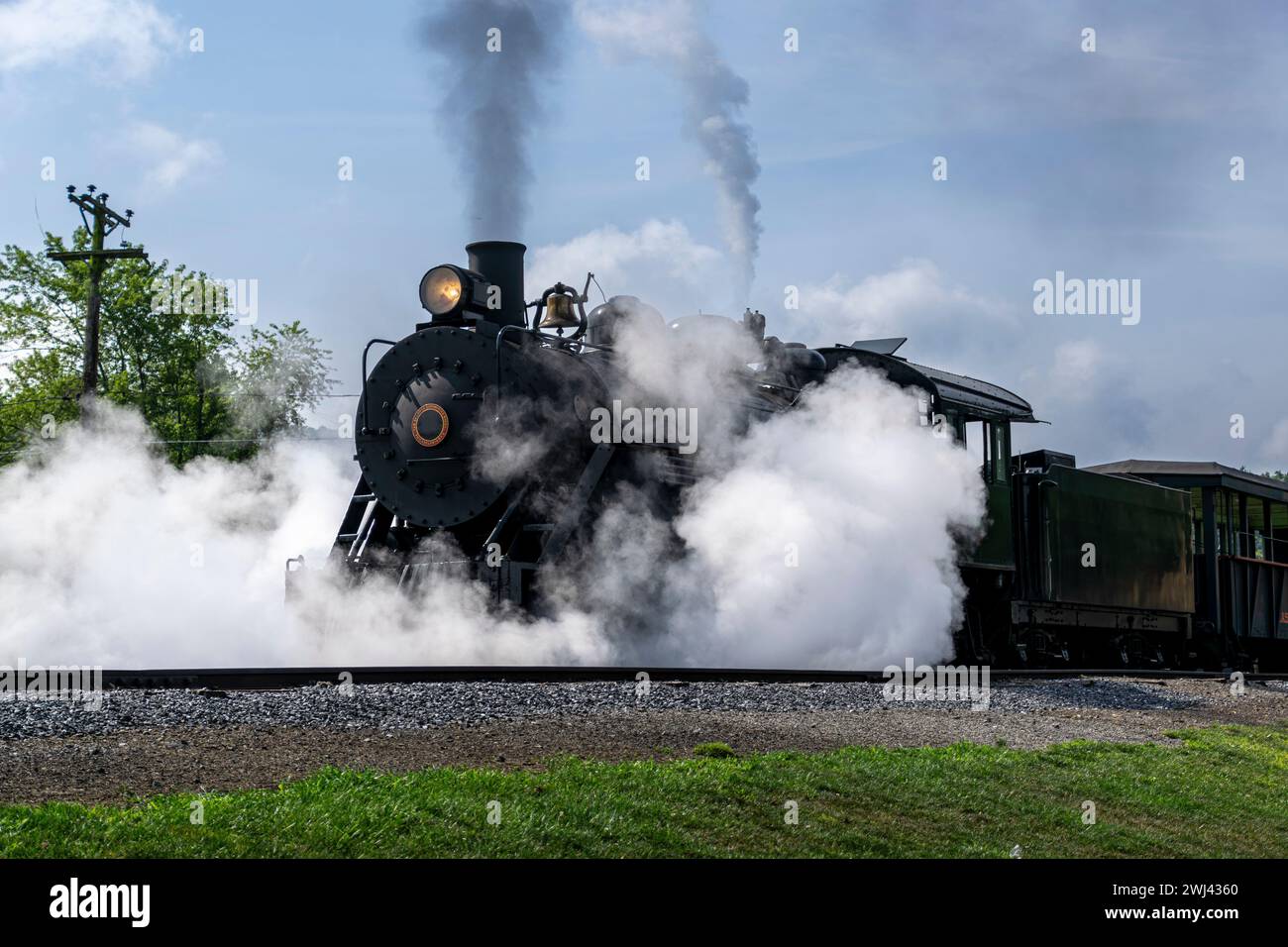 Vue d'un train de passagers à vapeur à voie étroite restaurée soufflant de la fumée et beaucoup de vapeur Banque D'Images