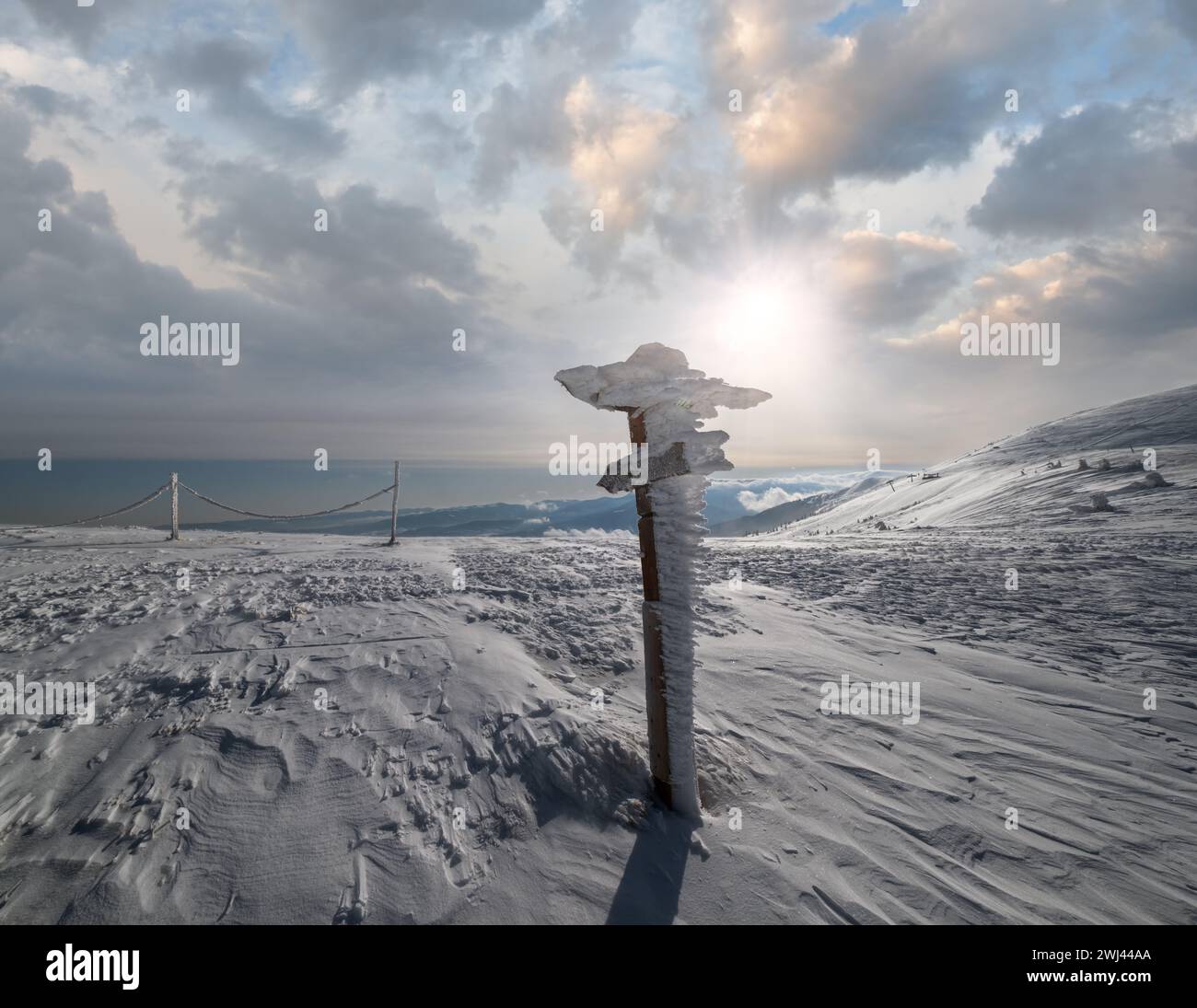 Pointeur couvert de neige près du chemin sur le plateau de montagne enneigé et le soleil dans le ciel. Magnifique journée ensoleillée sur une belle alpe pittoresque Banque D'Images