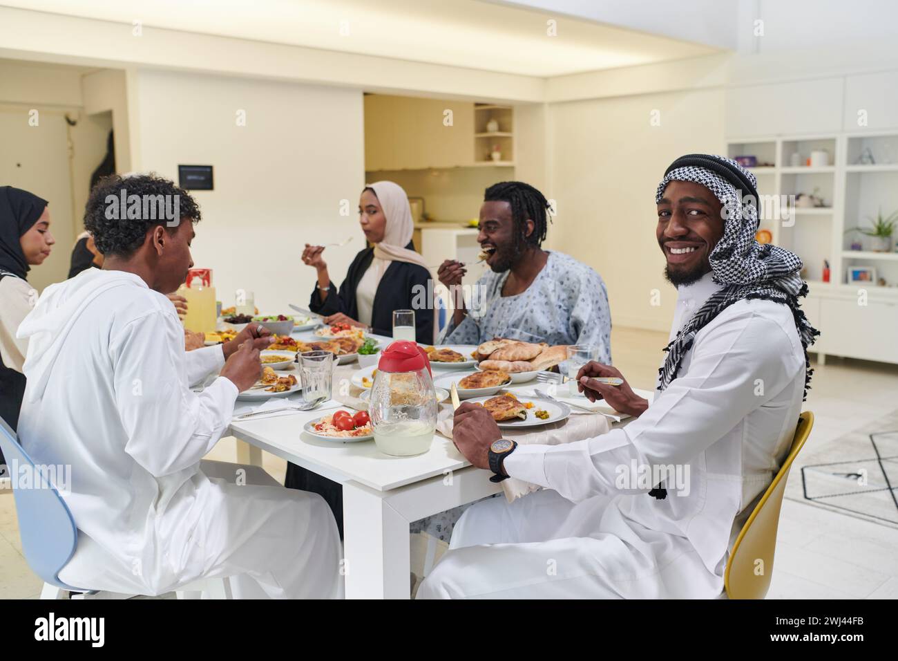 Une famille musulmane traditionnelle et diversifiée se réunit pour partager un délicieux repas iftar pendant le mois sacré du Ramadan, Embod Banque D'Images