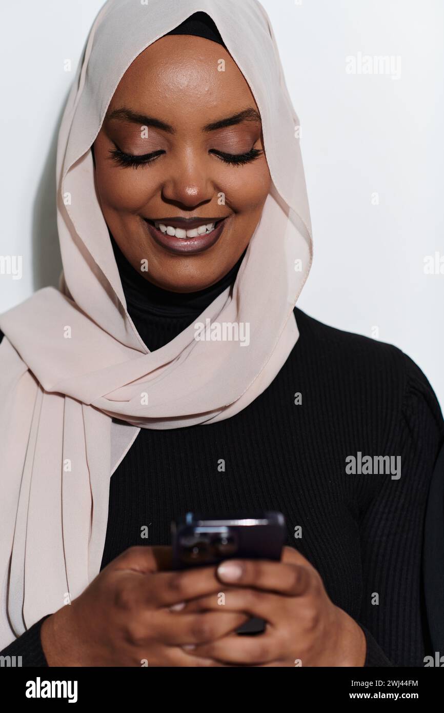 Une élégante femme arabe, ornée d’un hijab, s’engage dans la modernité en utilisant un smartphone, la juxtaposition de l’att traditionnel Banque D'Images