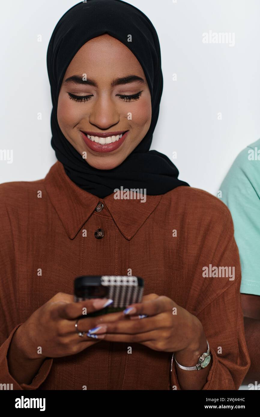 Une élégante femme arabe, ornée d’un hijab, s’engage dans la modernité en utilisant un smartphone, la juxtaposition de l’att traditionnel Banque D'Images