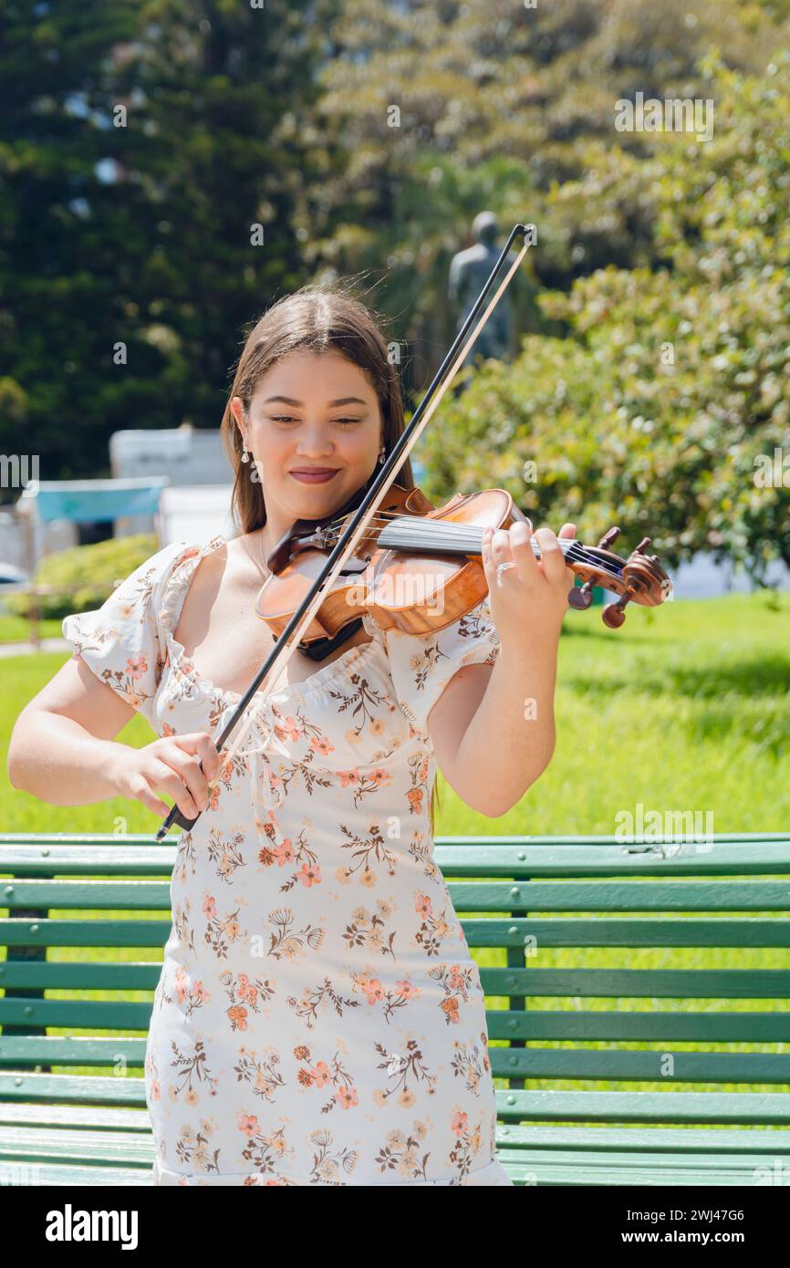 portrait vertical de jeune latin busker femme violoniste jouant du violon dans le parc heureux sourire inspiré. copier l'espace. Banque D'Images