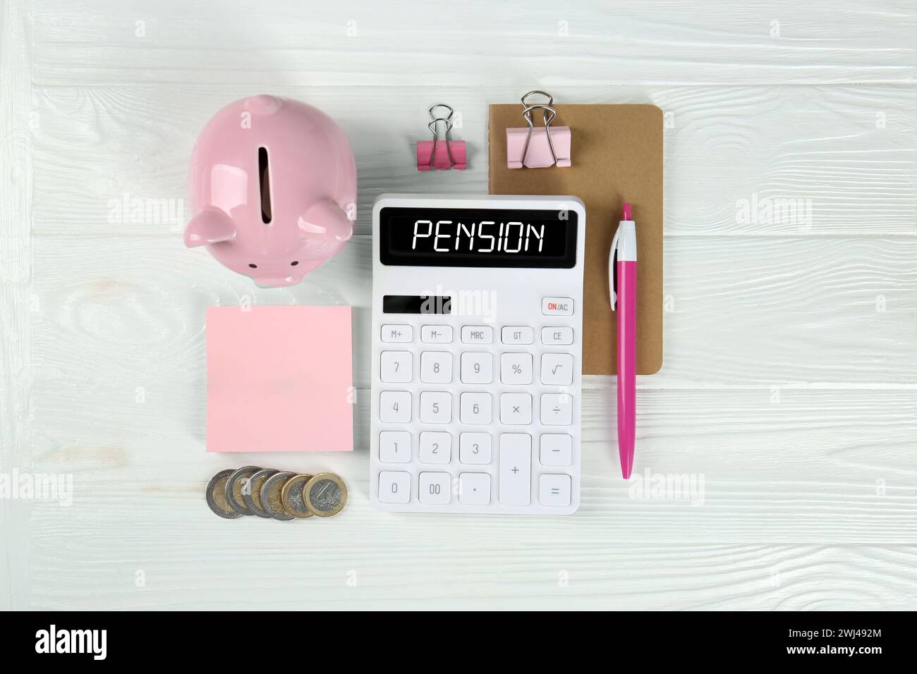 Calculatrice avec mot pension, pièces de monnaie, tirelire et papeterie sur table en bois blanc, plat Banque D'Images