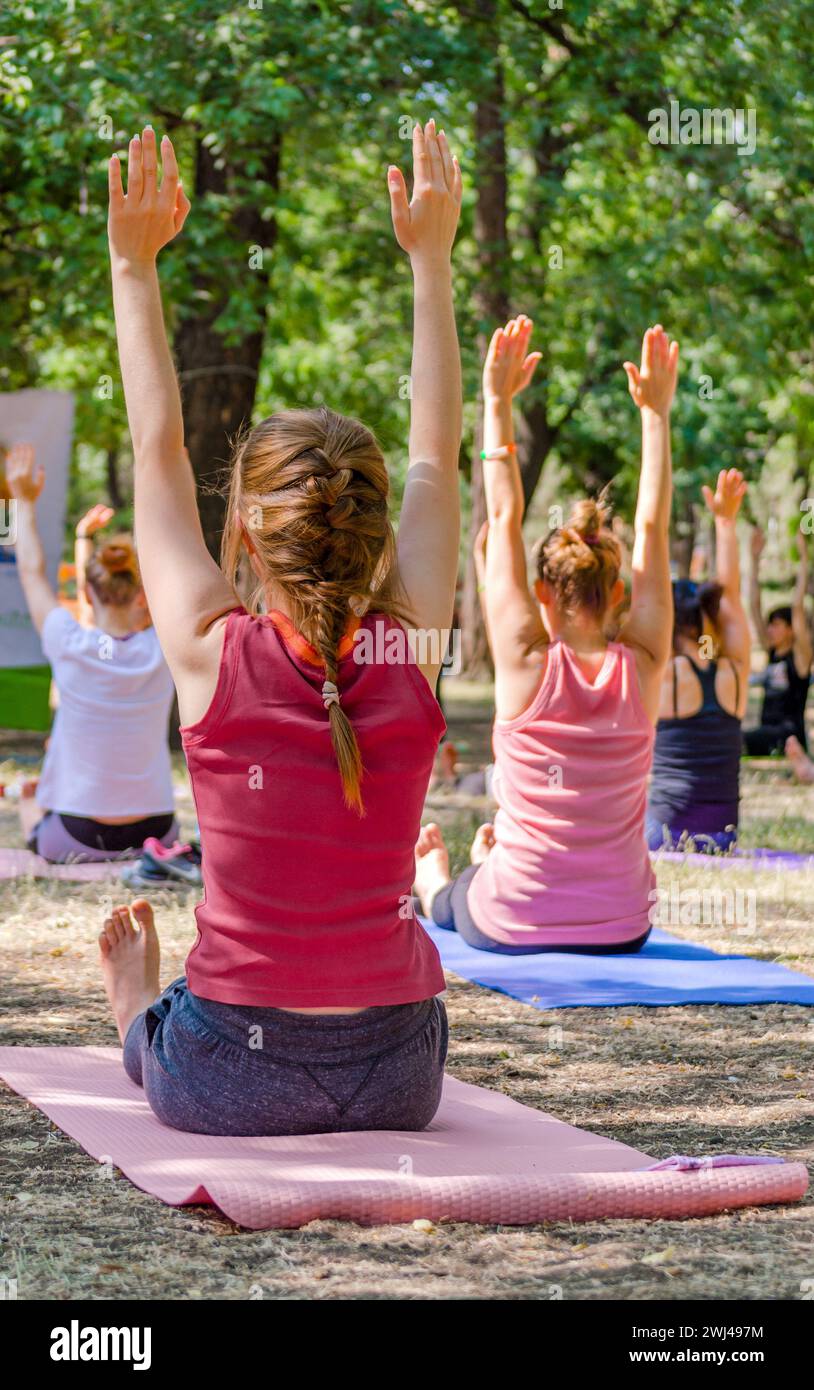 Yoga dans un parc un groupe de personnes assis sur des yogamates tenant Th Banque D'Images Yoga dans un parc un groupe de personnes assis sur des yogamates tenant Th Banque D'Images