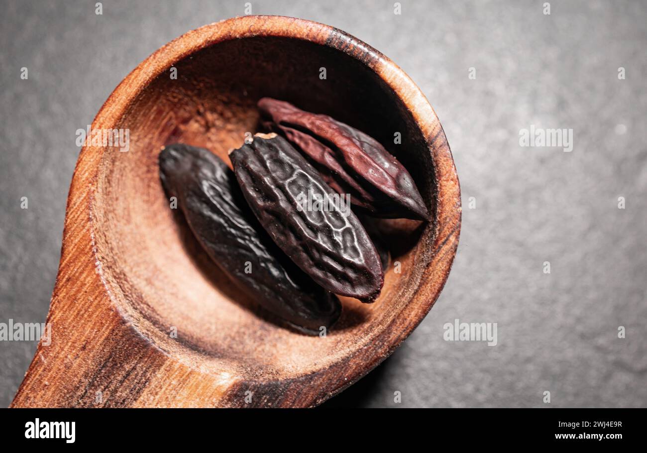 Haricots Tonka dans une cuillère en bois sur un fond sombre Banque D'Images