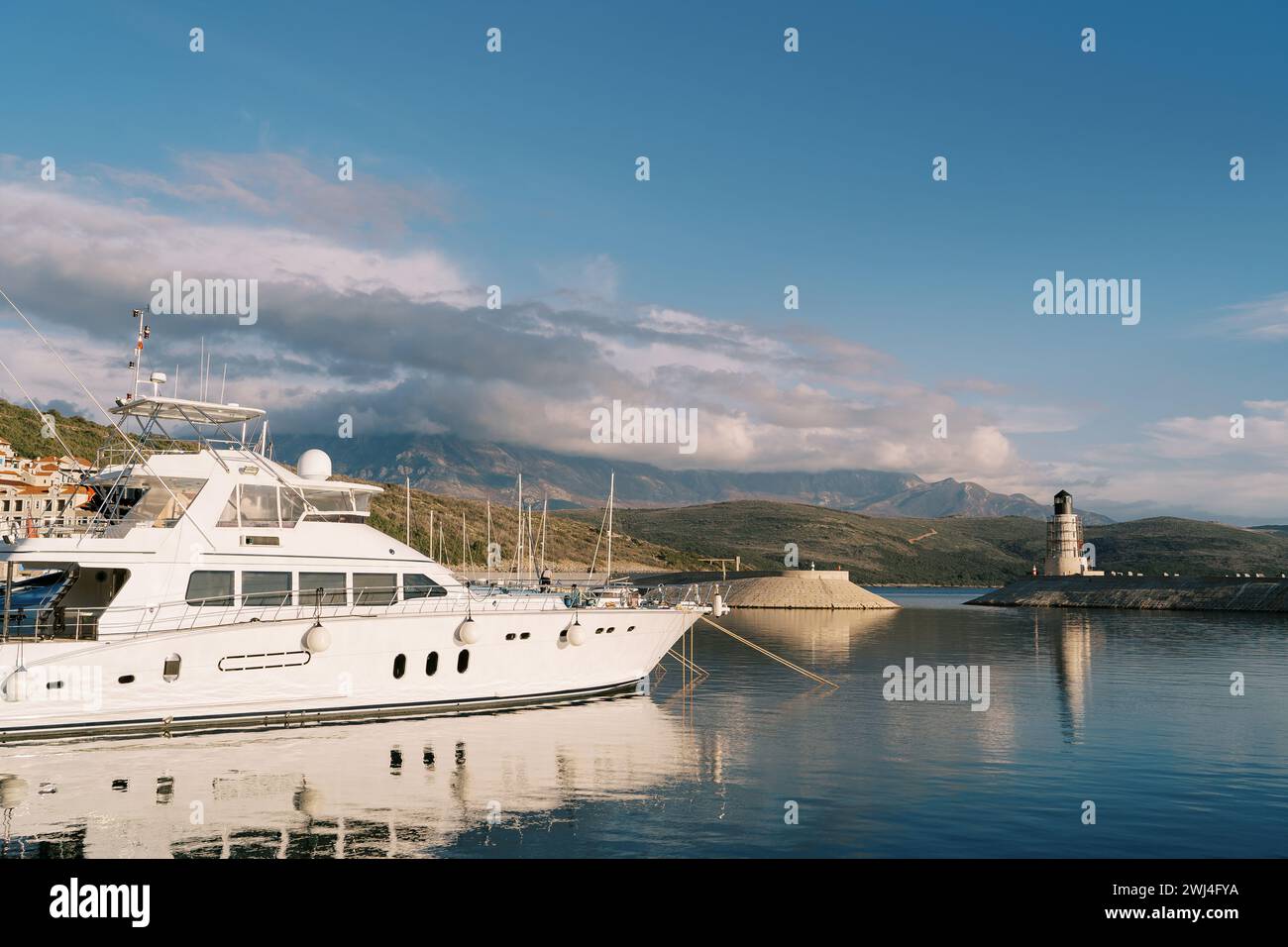 Yacht à moteur se dresse sur la jetée surplombant le phare au pied des montagnes Banque D'Images