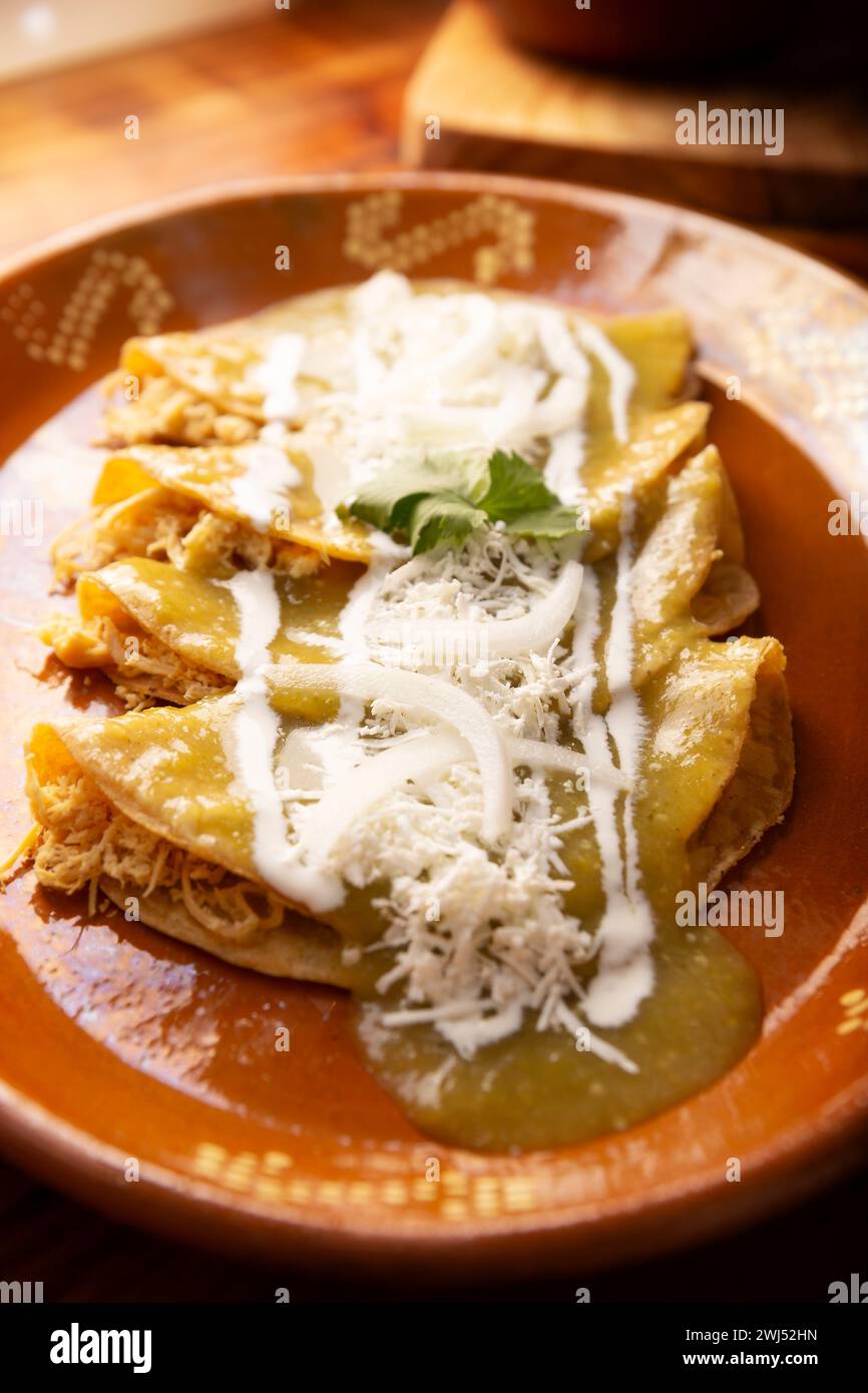 Enchiladas vertes. Plat mexicain typique fait avec une tortilla de maïs pliée ou roulée remplie de poulet râpé et recouverte de sauce verte épicée, cre Banque D'Images