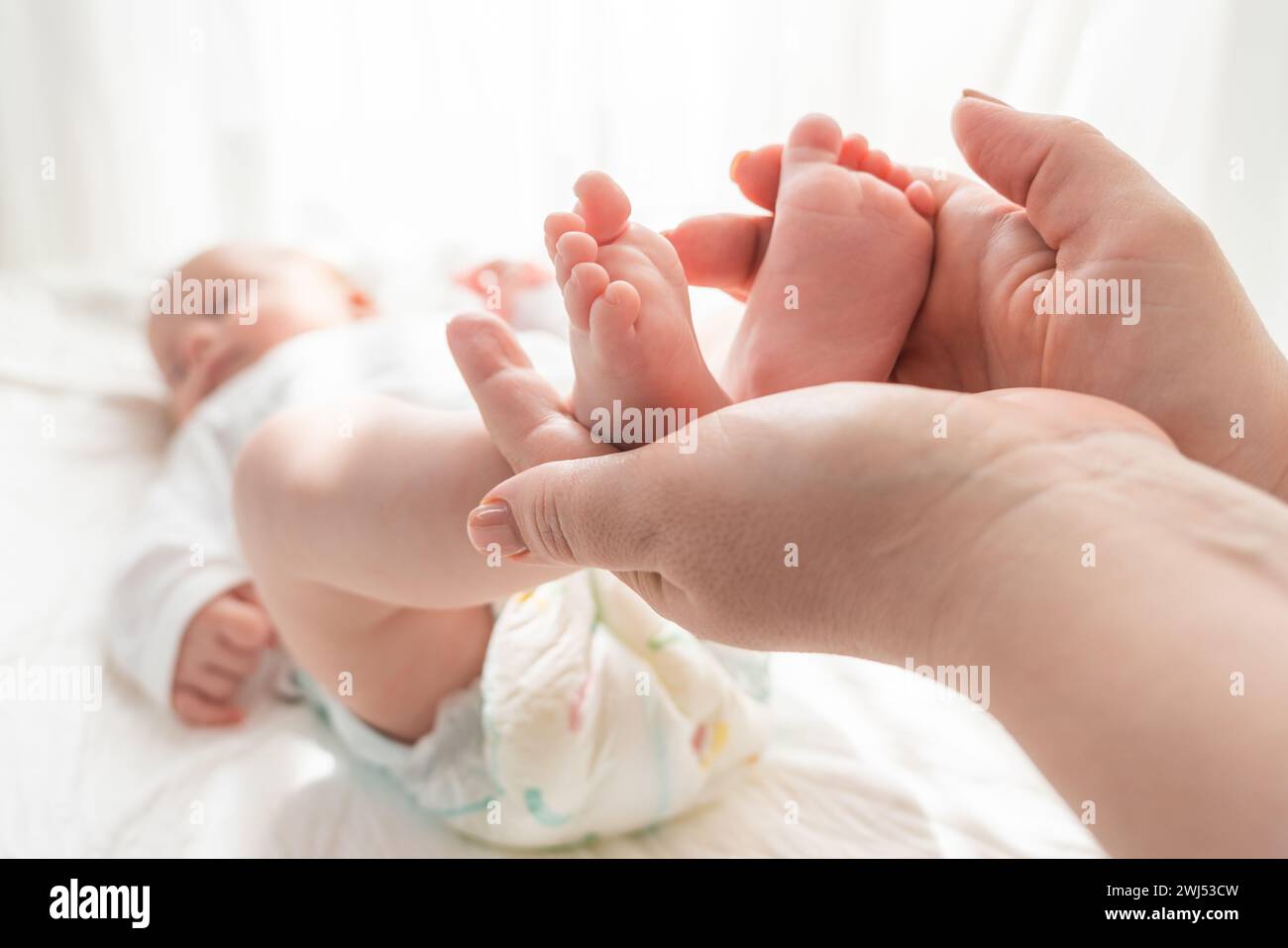 Mère chérit les pieds délicats de son enfant, concept d'amour maternel et de tendresse Banque D'Images