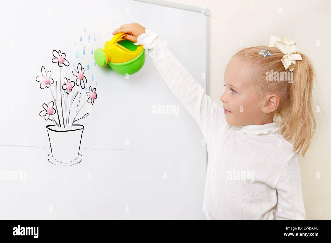 Fille arrosage fleur dessin sur un tableau blanc Banque D'Images