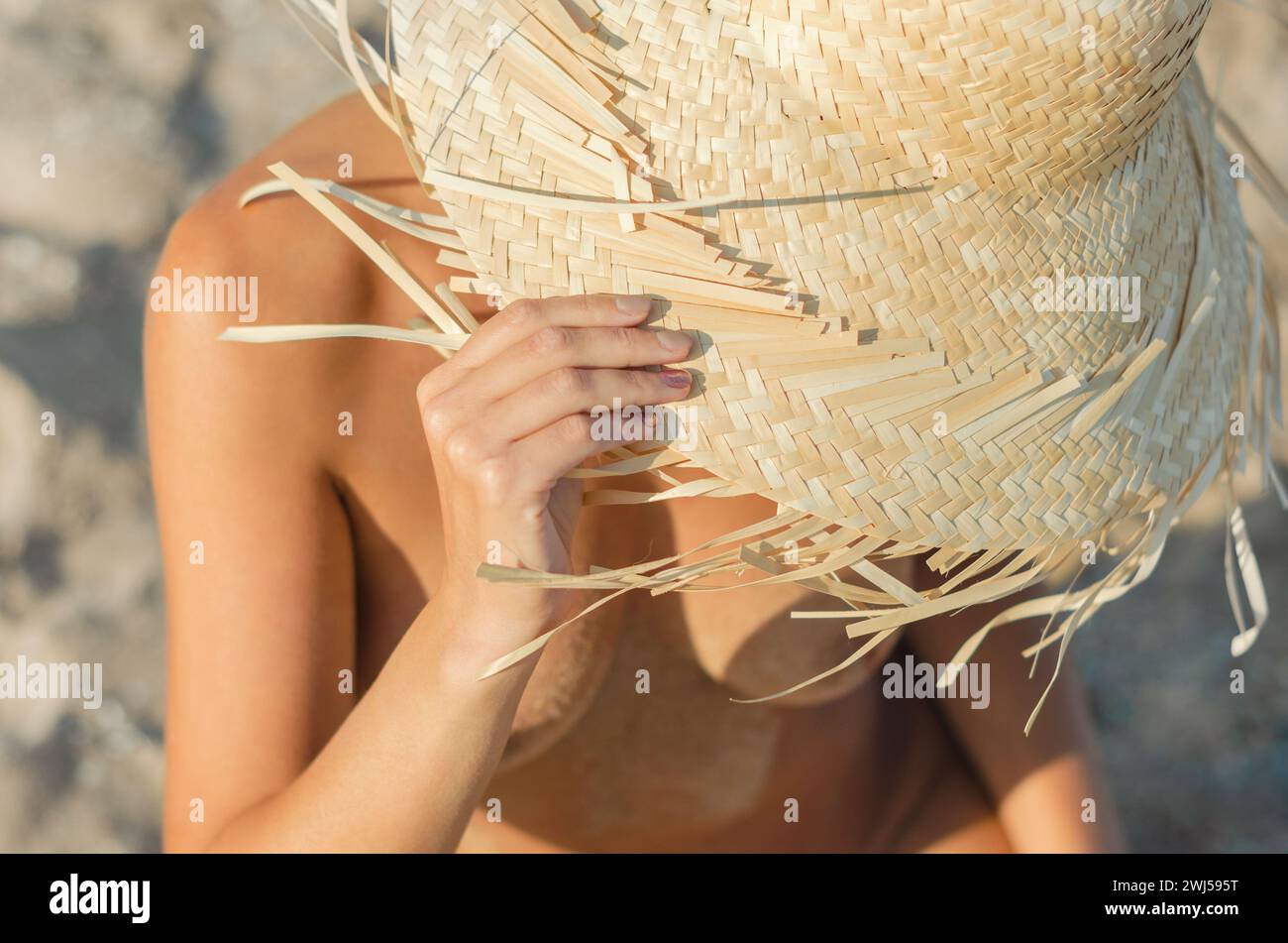 Jeune fille dans un chapeau de paille assis sur le sable à la plage de près Banque D'Images