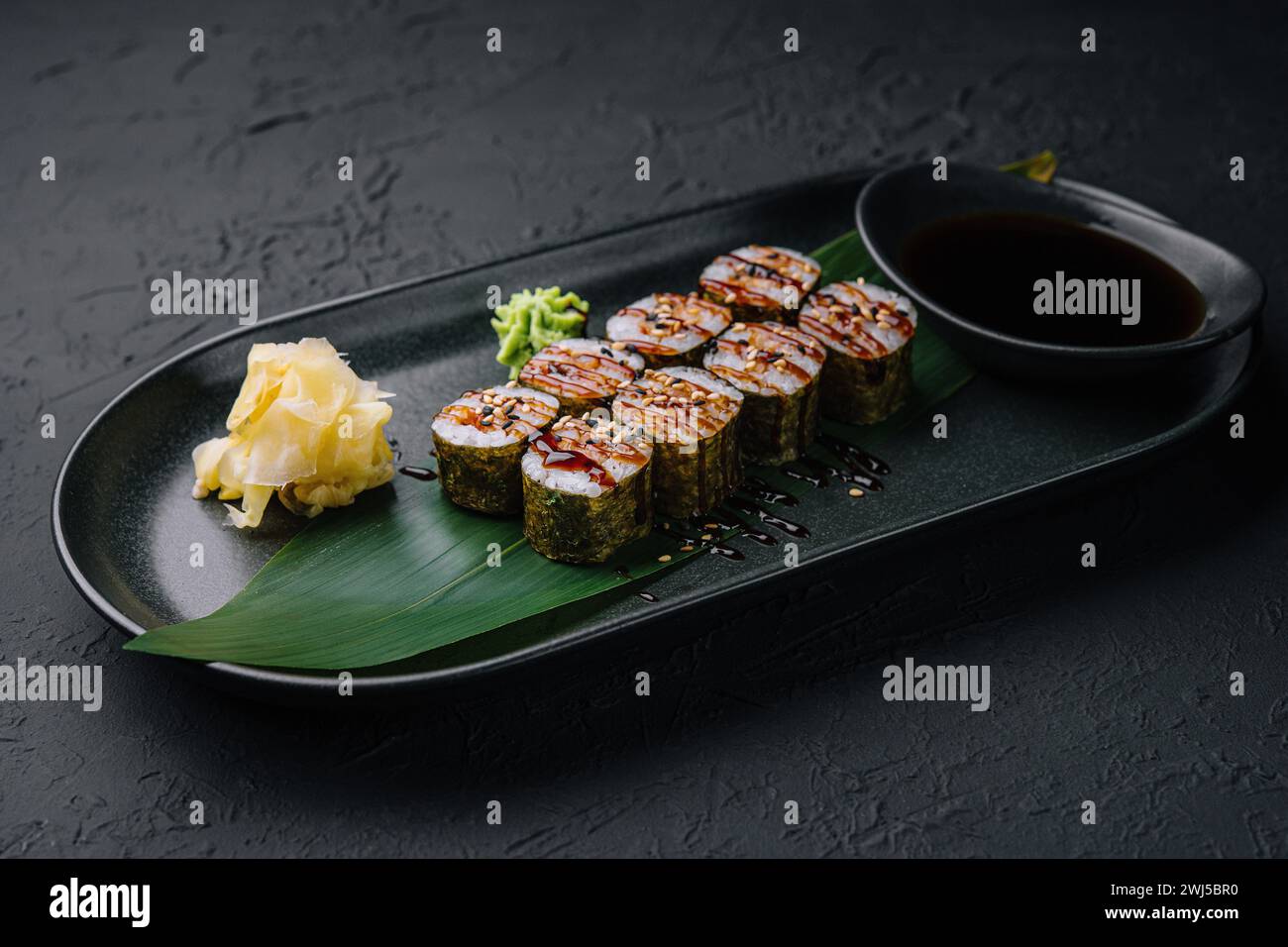 Futomaki traditionnel de sushi japonais frais sur assiette noire Banque D'Images