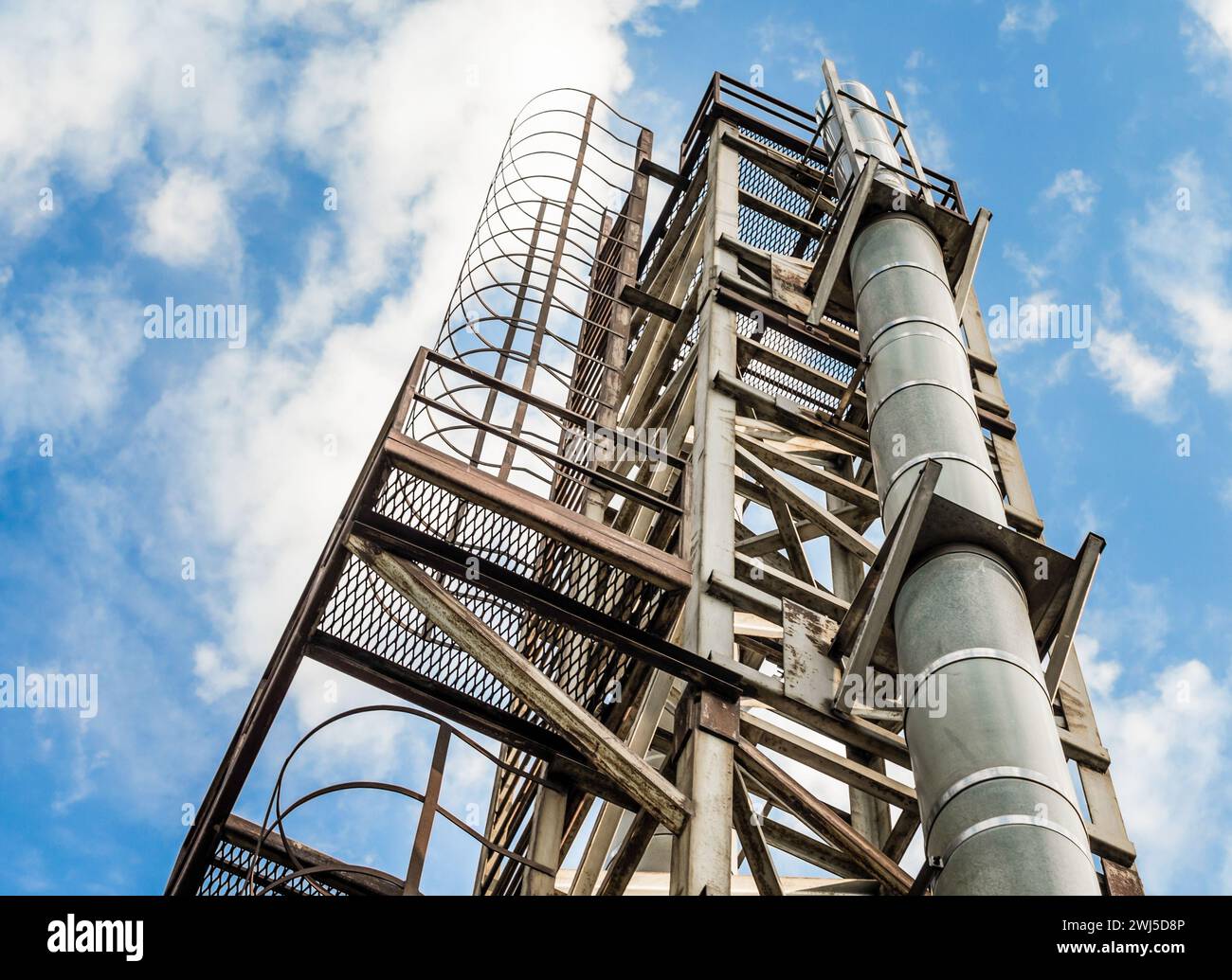 Tour avec un tuyau et une échelle contre un ciel bleu et des nuages Banque D'Images Tour avec un tuyau et une échelle contre un ciel bleu et des nuages Banque D'Images