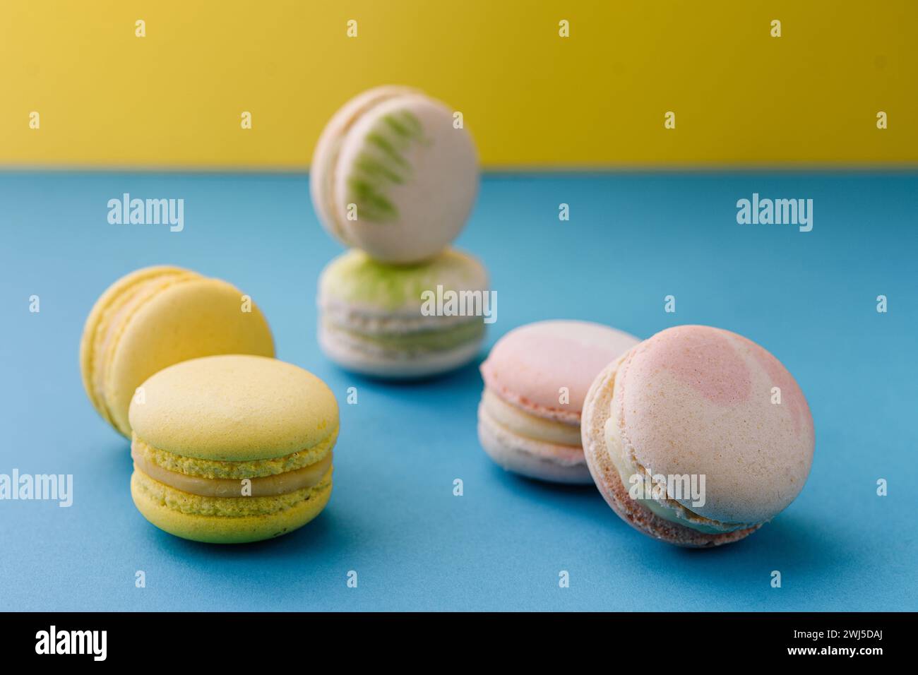 Macarons doux et colorés sur bleu avec fond jaune Banque D'Images