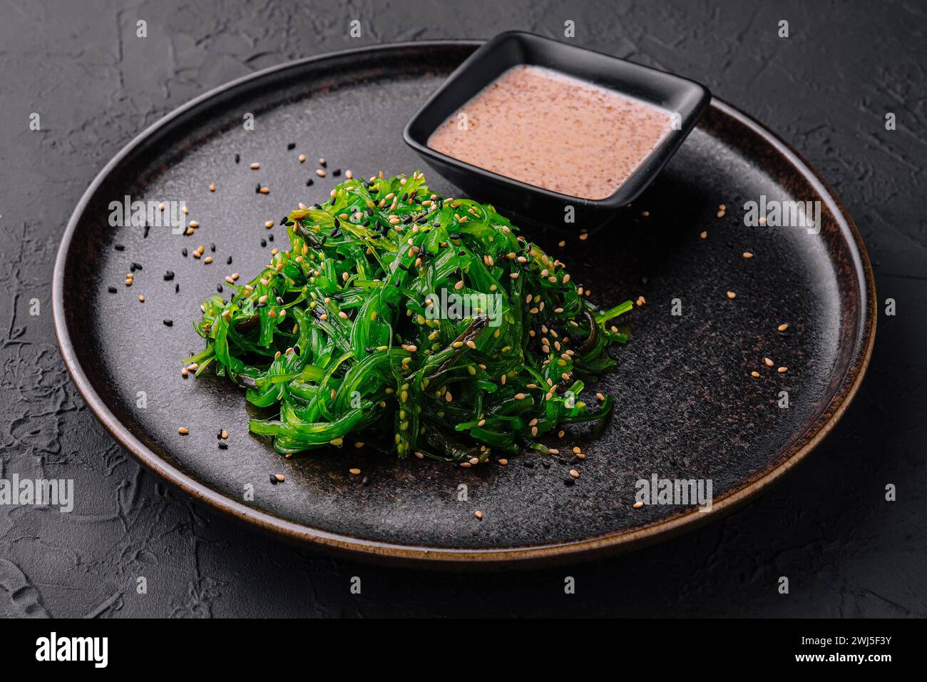 Salade d'algues wakame avec graines de sésame sur plaque noire Banque D'Images
