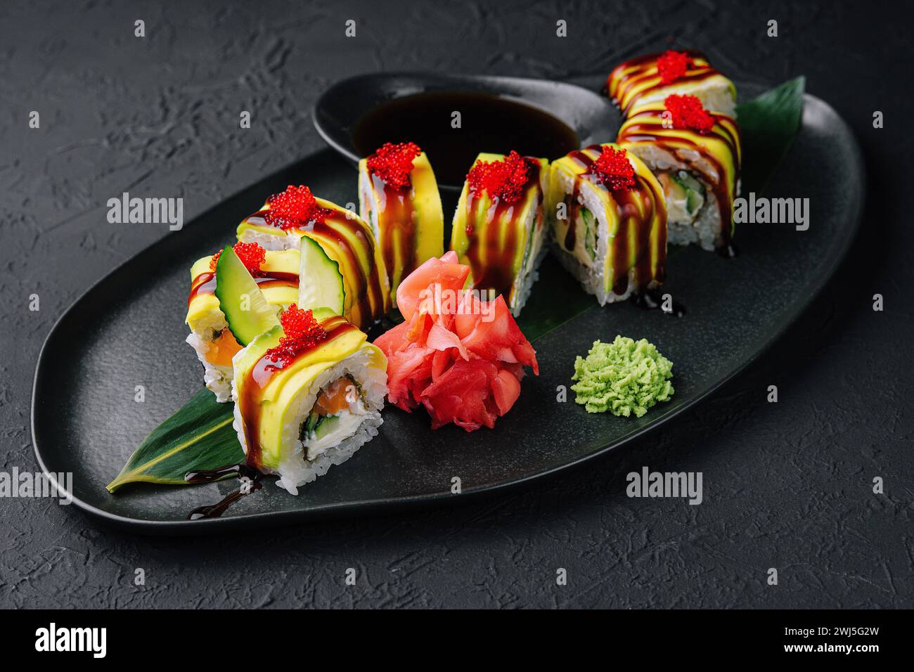 Rouleau de sushi dragon vert avec anguille sur pierre noire Banque D'Images