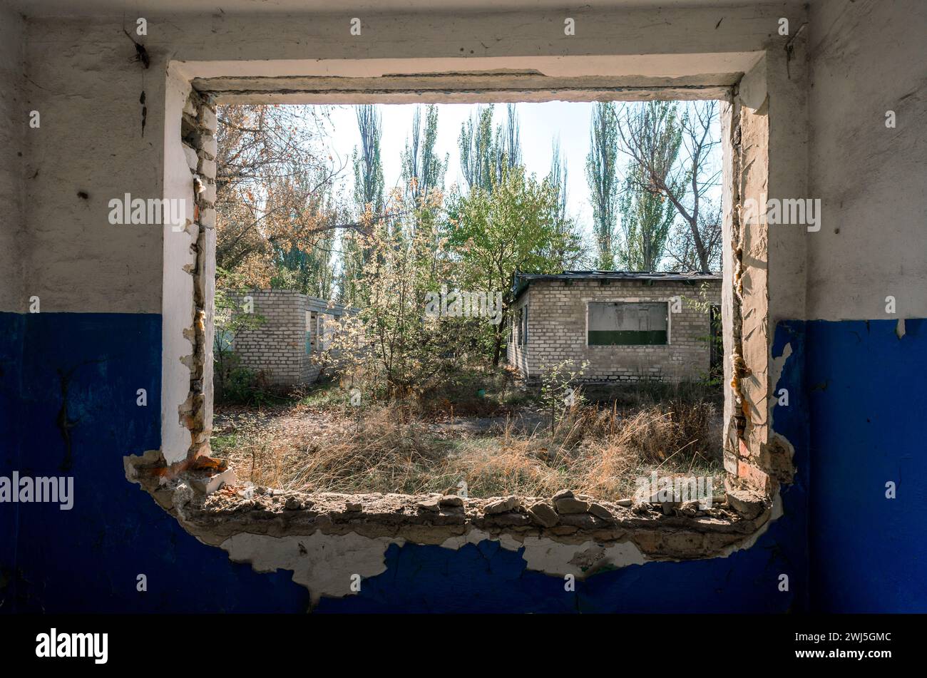 Vue depuis la fenêtre d'une maison abandonnée abandonnée dans le village d'Ukraine Banque D'Images