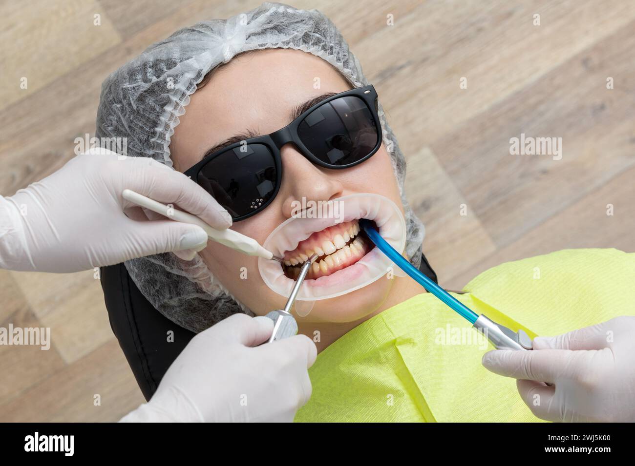 Patient avec enrouleur de joue allongé dans le cabinet du dentiste Banque D'Images Patient avec enrouleur de joue allongé dans le cabinet du dentiste Banque D'Images
