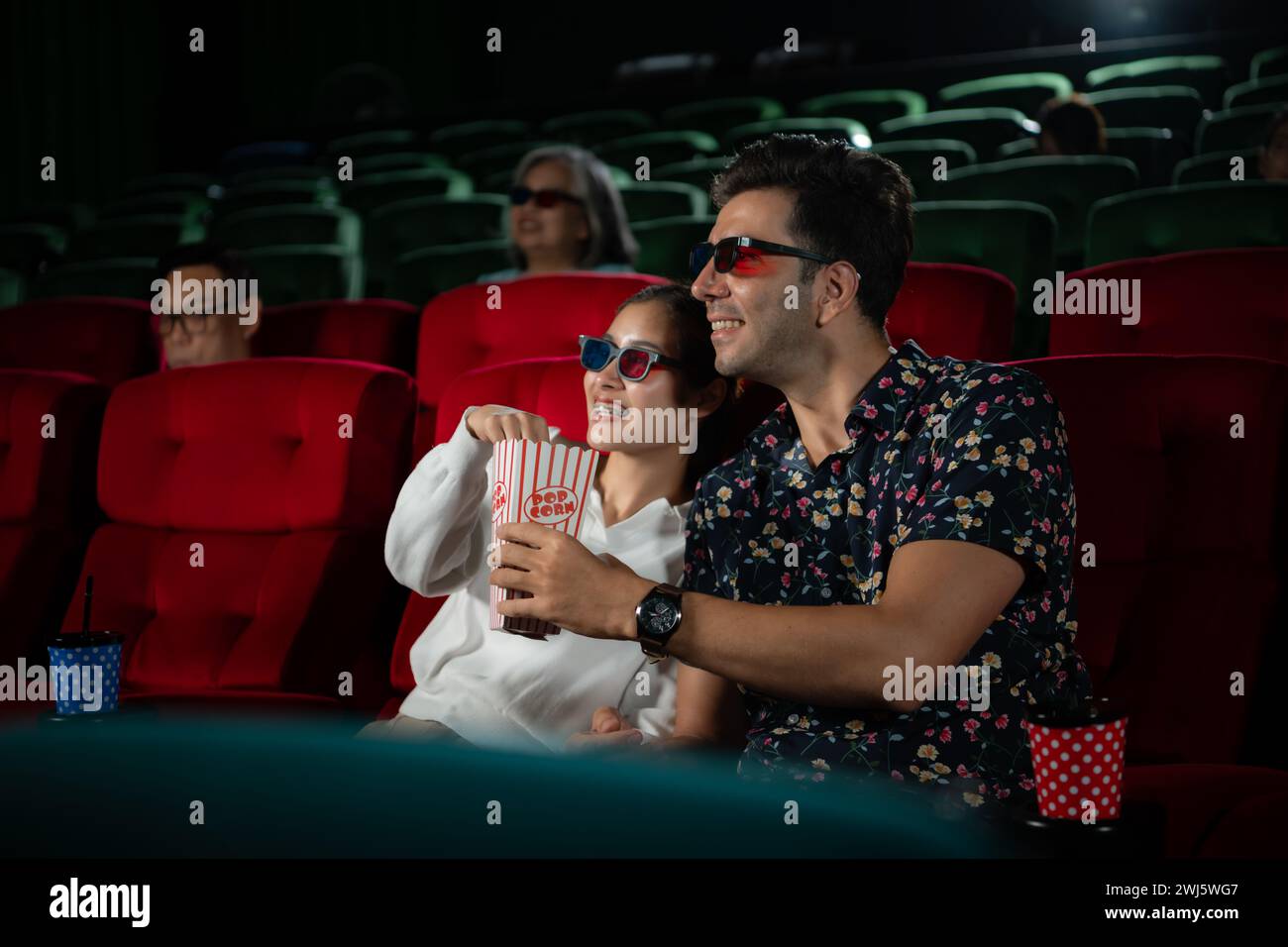 Dans un cinéma, Un jeune couple portant des lunettes 3D regarde des films et mange du pop-corn. Banque D'Images