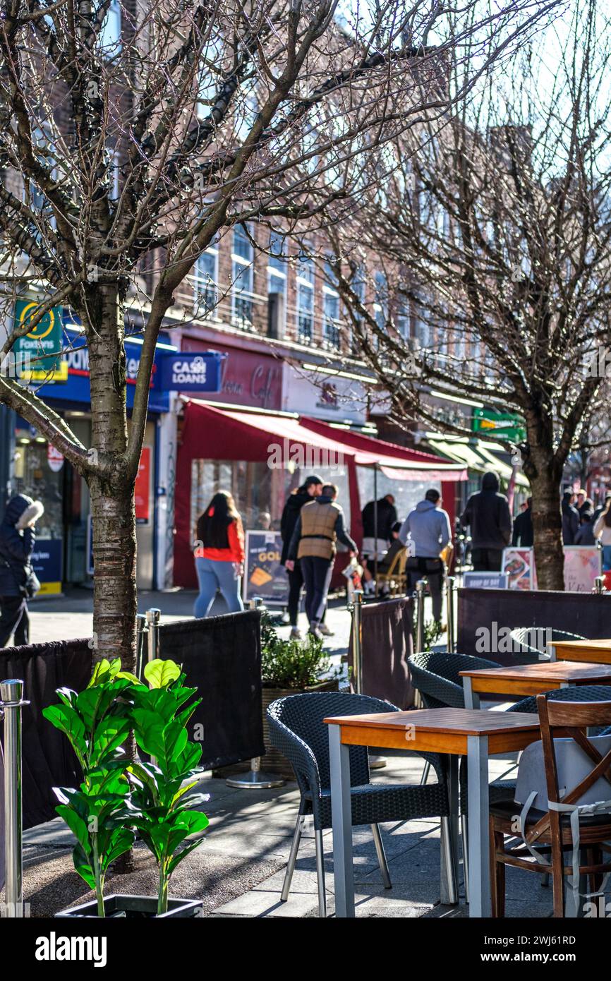 Kingston-upon-Thames, Londres, Royaume-Uni, 12 février 2024, des gens marchant le long d'une rue bordée de boutiques passant devant une terrasse de café vide Banque D'Images