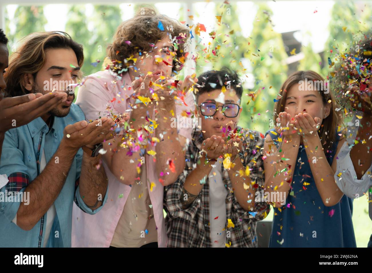 Groupe d'amis multiethniques s'amusant à la fête en jouant amusant souffler du papier coloré Banque D'Images